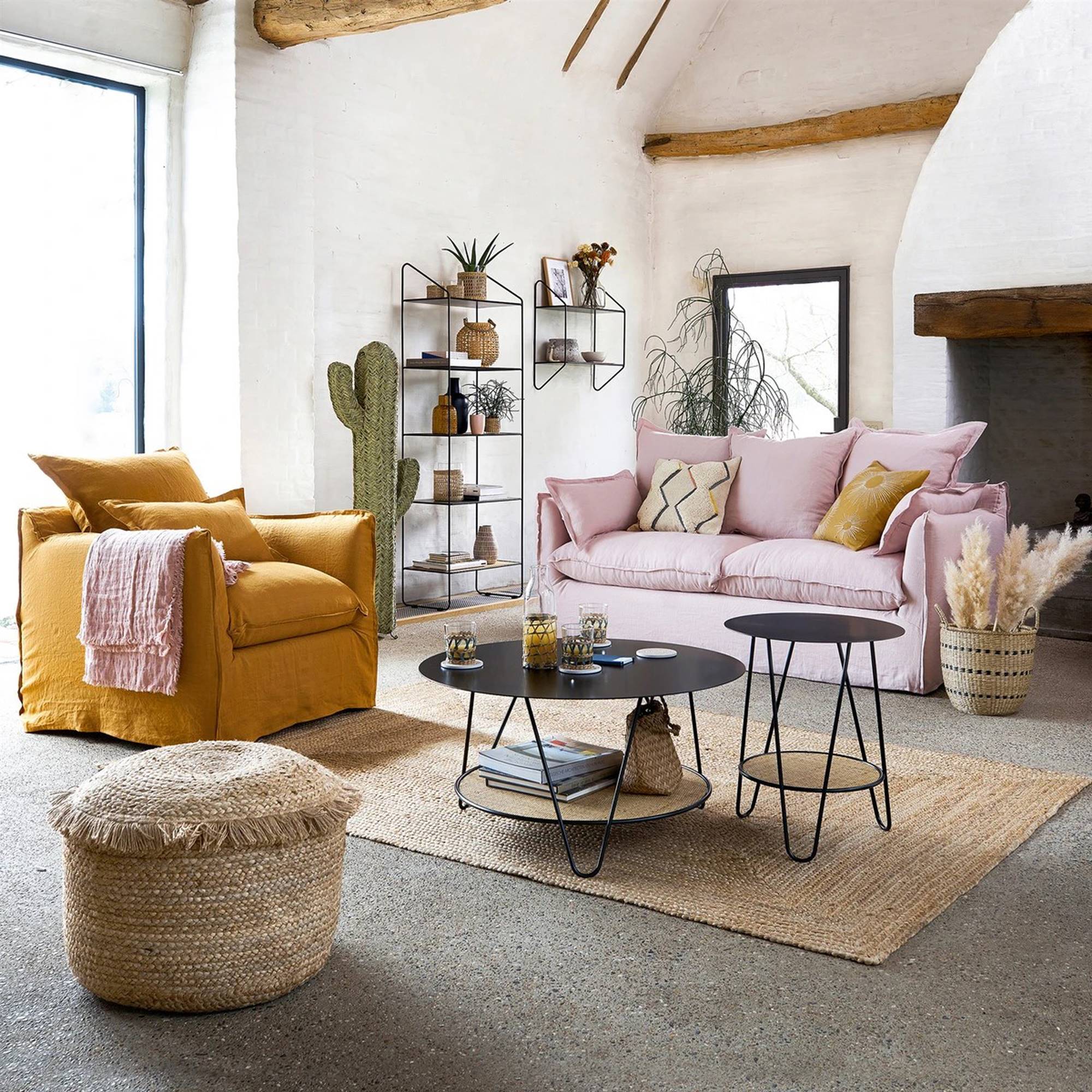 Salón con puff y alfombra de fibras, sofá rosa y butaca amarilla. 