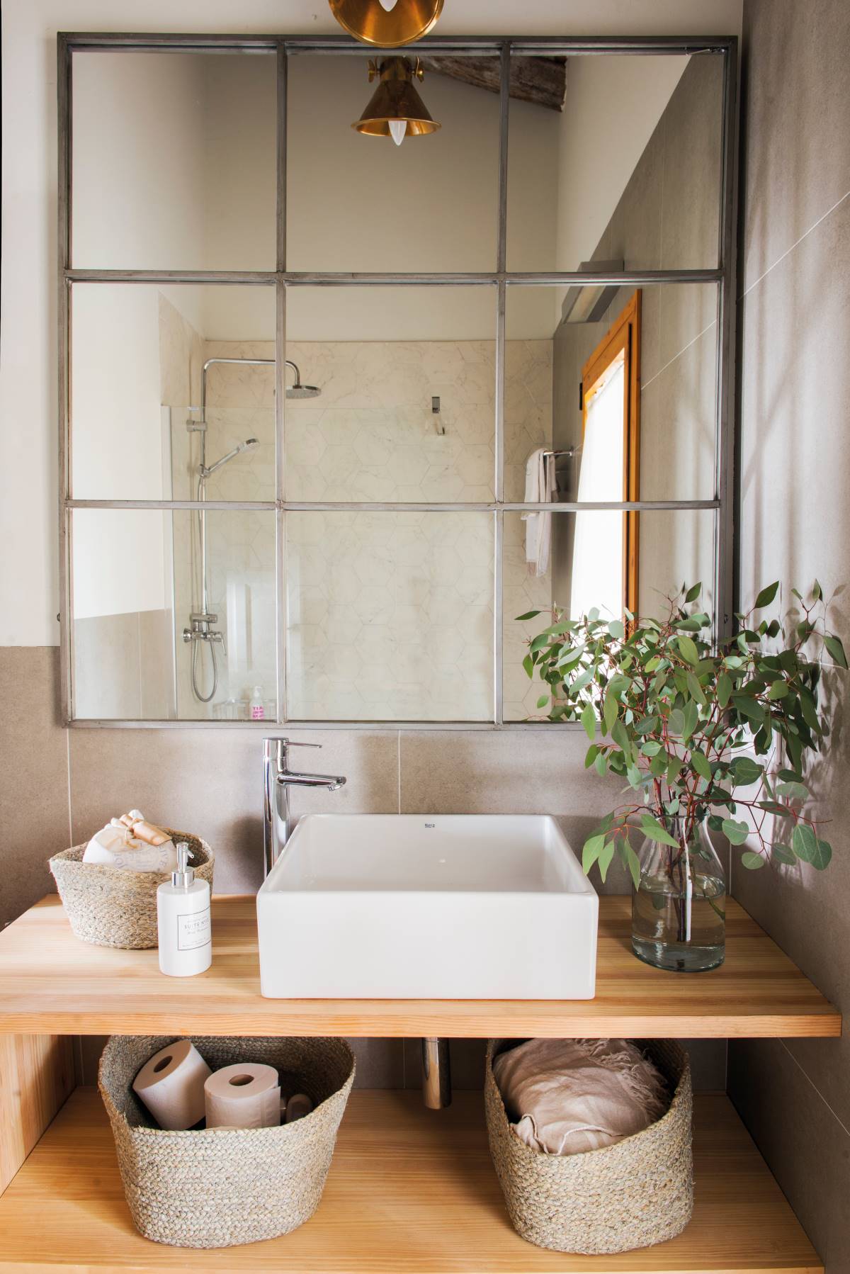 Baño con espejo tipo ventana y mueble de baño de madera con lavamanos sobre encimera. 