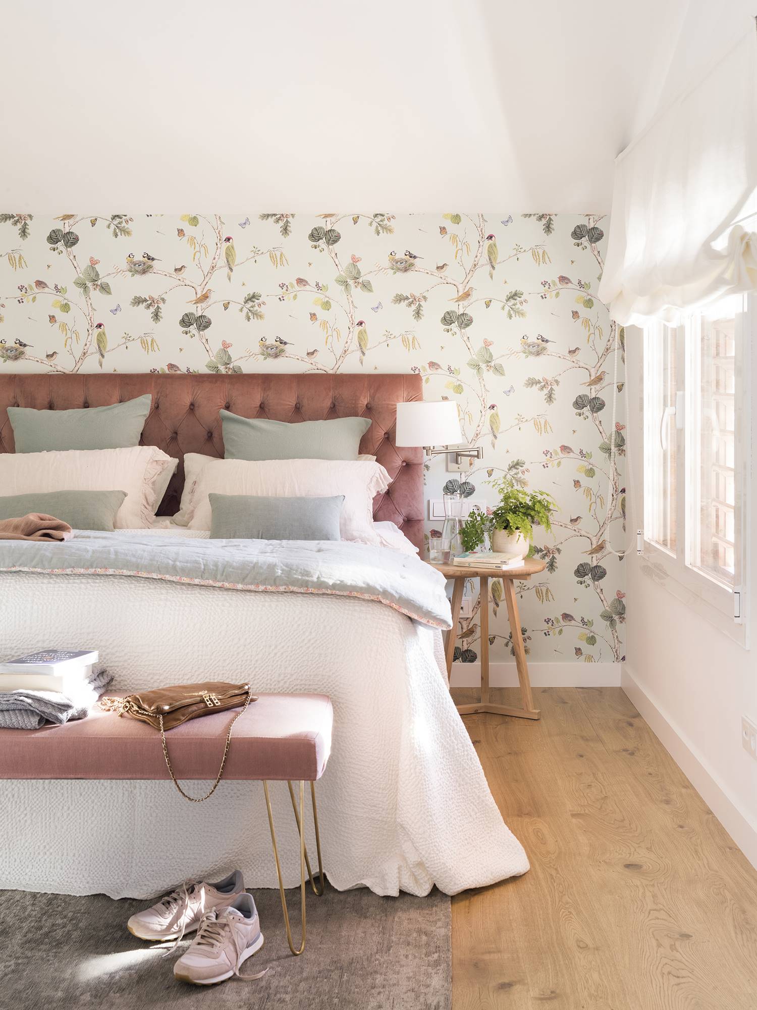 Dormitorio con papel pintado de flores y cabecero en capitoné rosa