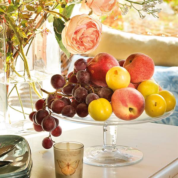 Detalle de vajilla, jarrón con flores y pastelero con fruta
