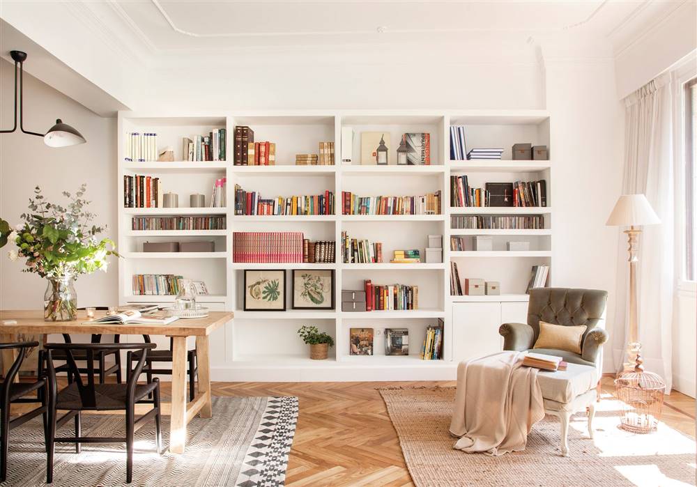 Salón con librería blanca a medida, techos con molduras y suelos de parquet de espiga
