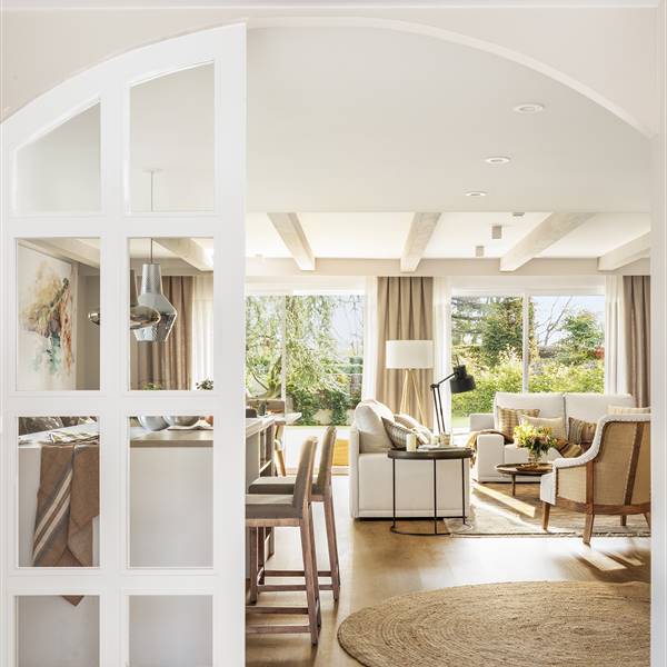Una espectacular casa con jardín y cocina abierta decorada en blanco y beige