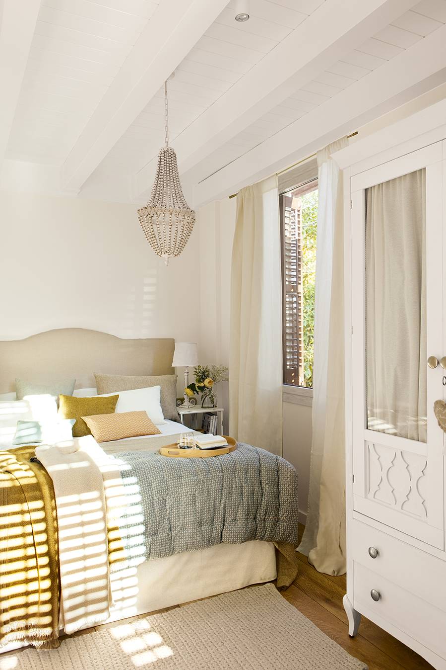 Dormitorio pequeño con techo de vigas en blanco, armario clásico y ropa de cama