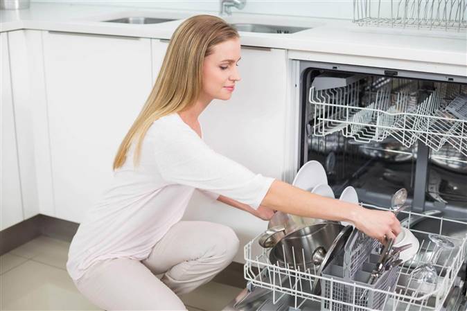 mujer metiendo cubiertos en el lavavajillas