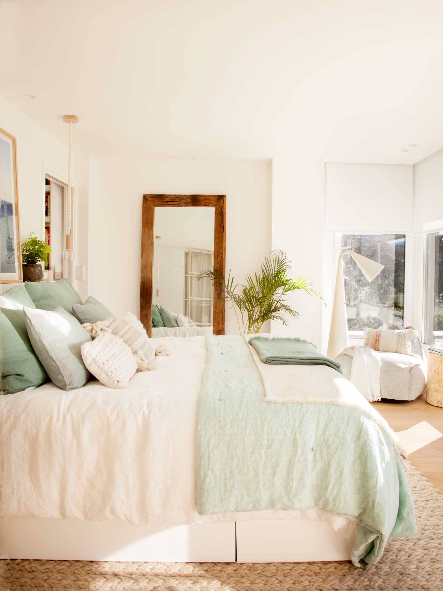 Dormitorio moderno en tonos blancos con espejo de pie y ventanal. 