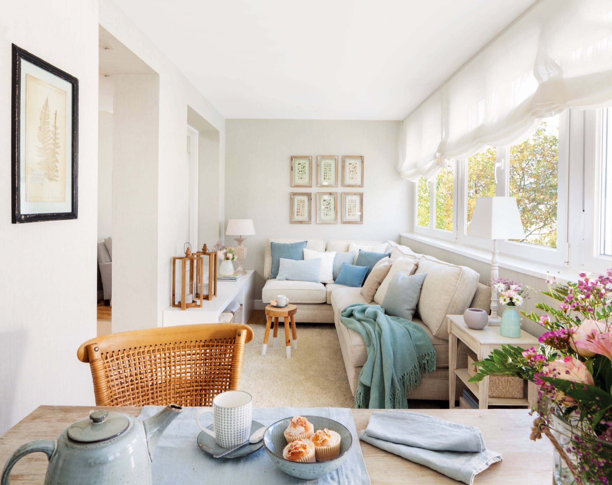 Sala de estar decorada en tonos blancos con cojines azules y un espacio para merendar