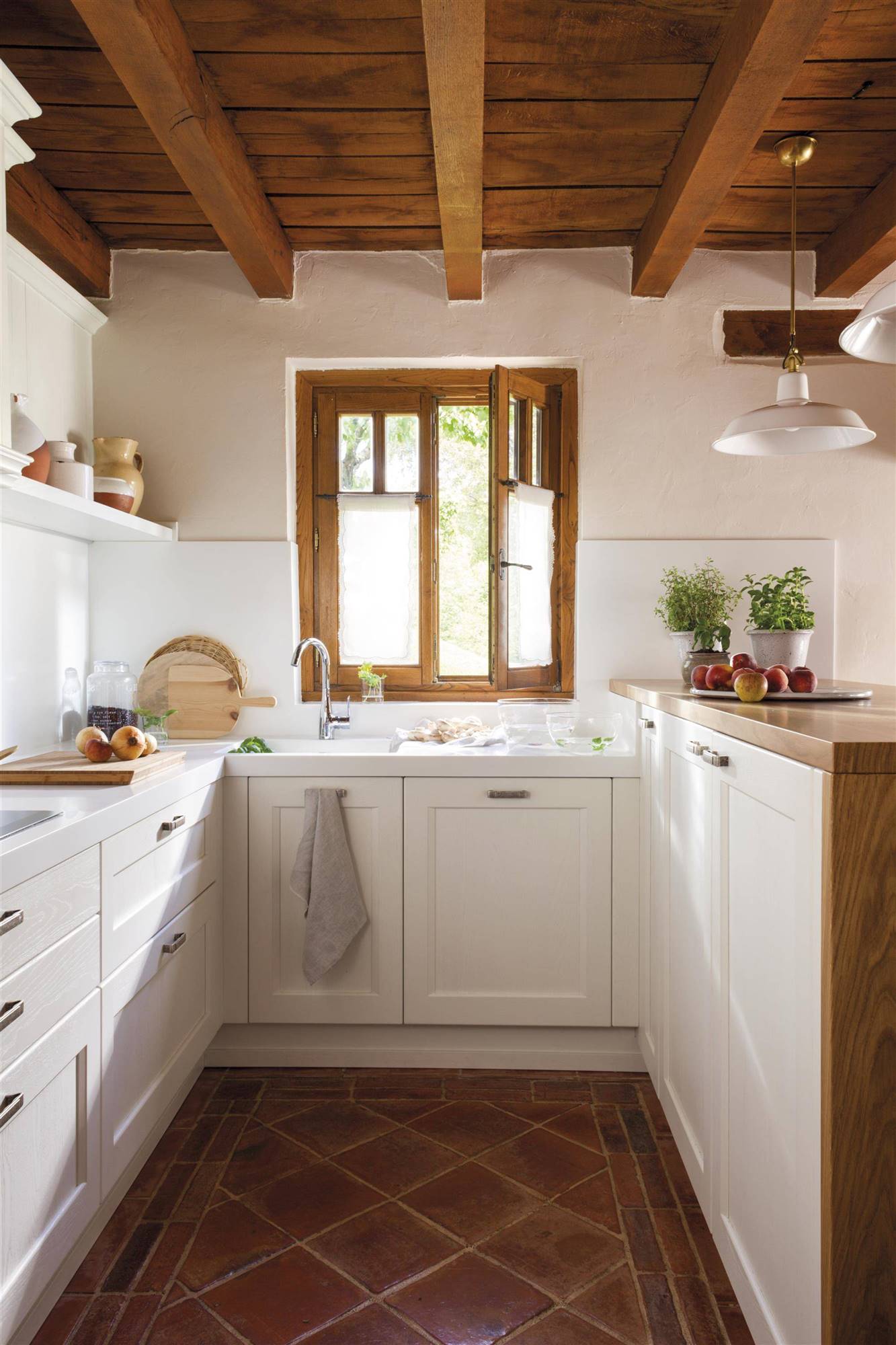 Cocina pequeña con techos y ventanas de madera, suelos de pavimento y armarios de cocina blancos- 461030