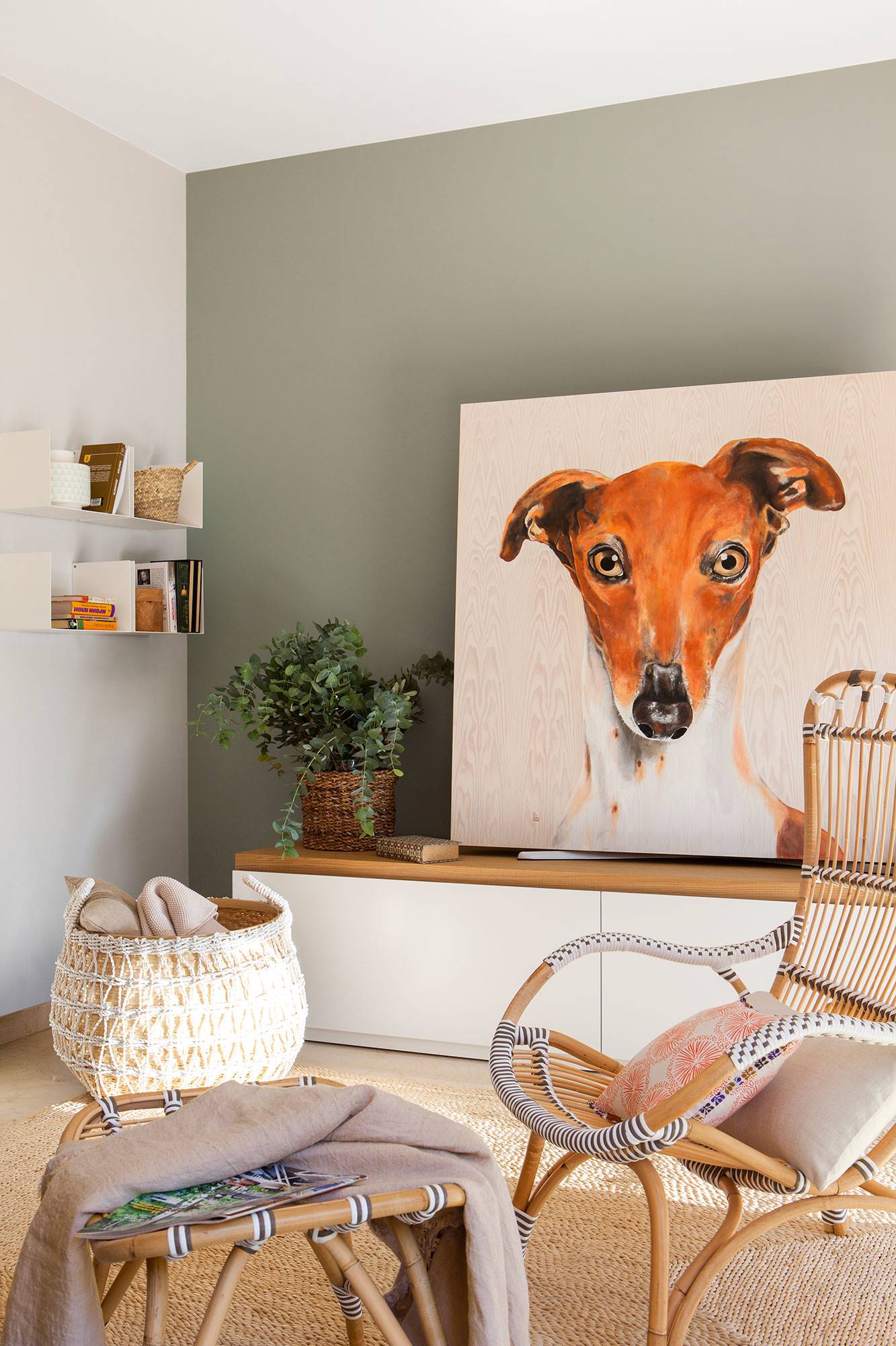 Rincón de salón con mueble bajo con cuadro de perro y butaca en primer plano