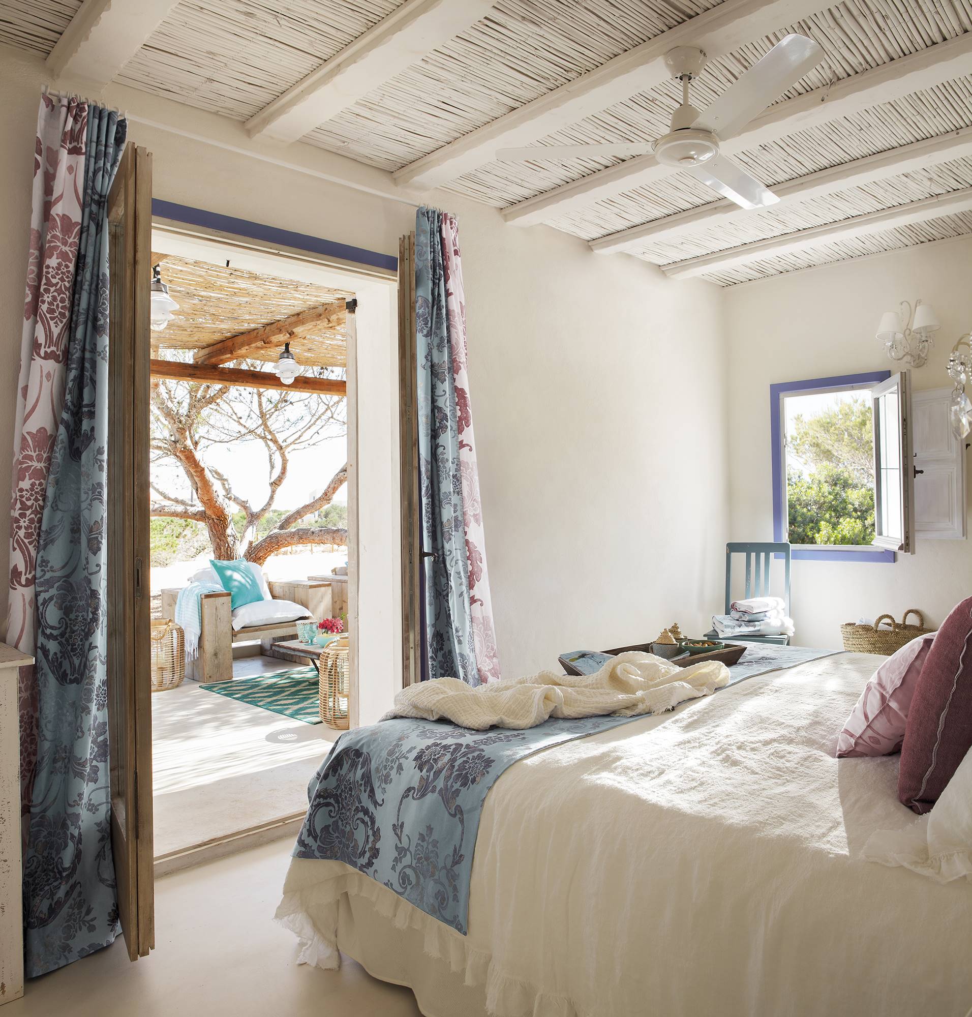 Dormitorio en blanco con detalles en azul y lila y vistas al salón de verano