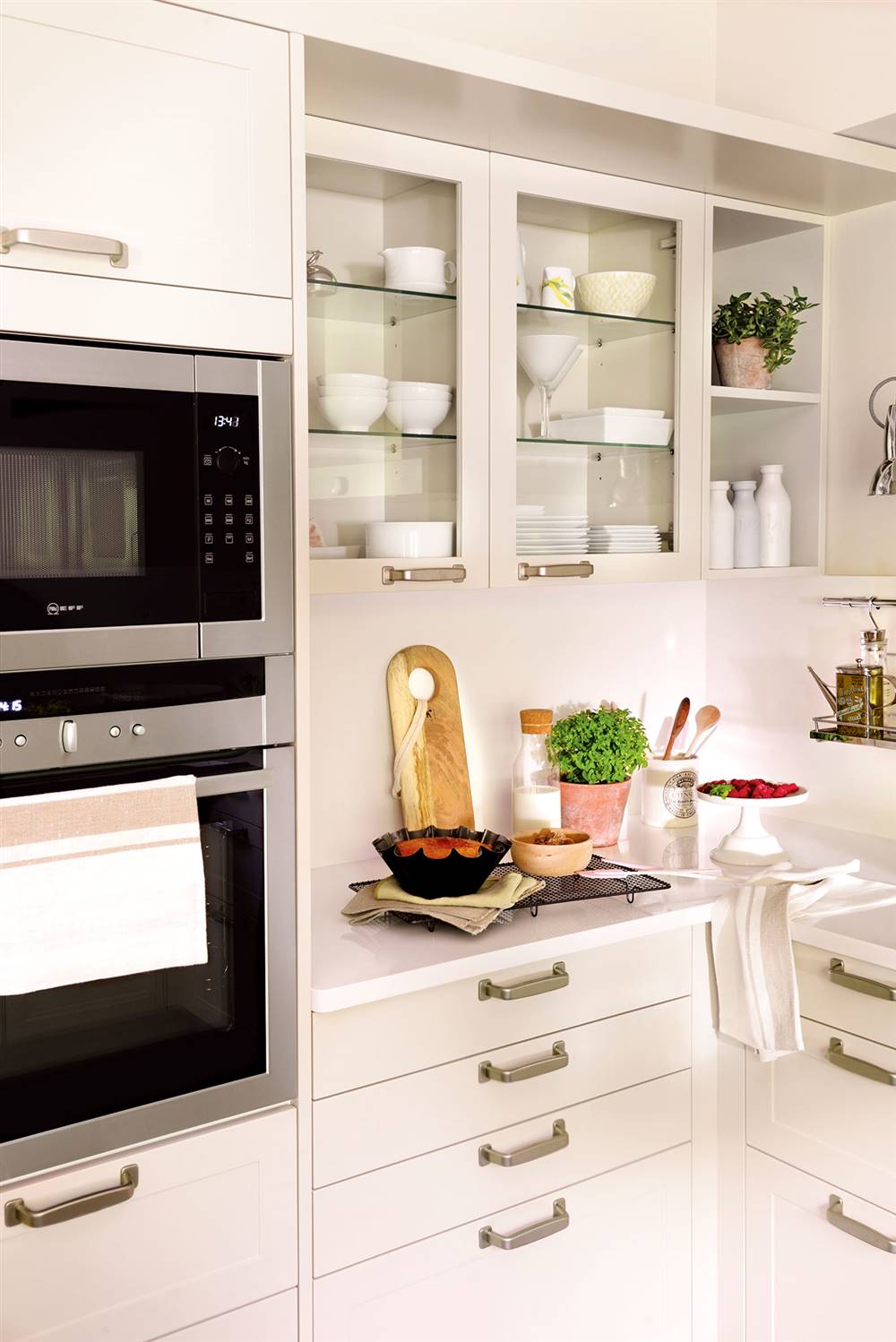 Semitoma cocina con muebles en blanco, cajones, vitrinas y horno y microondas en columna