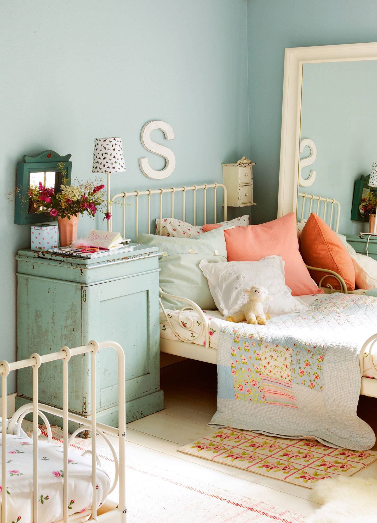 Detalle de habitación infantil con cama de hierro en blanco y paredes en azul