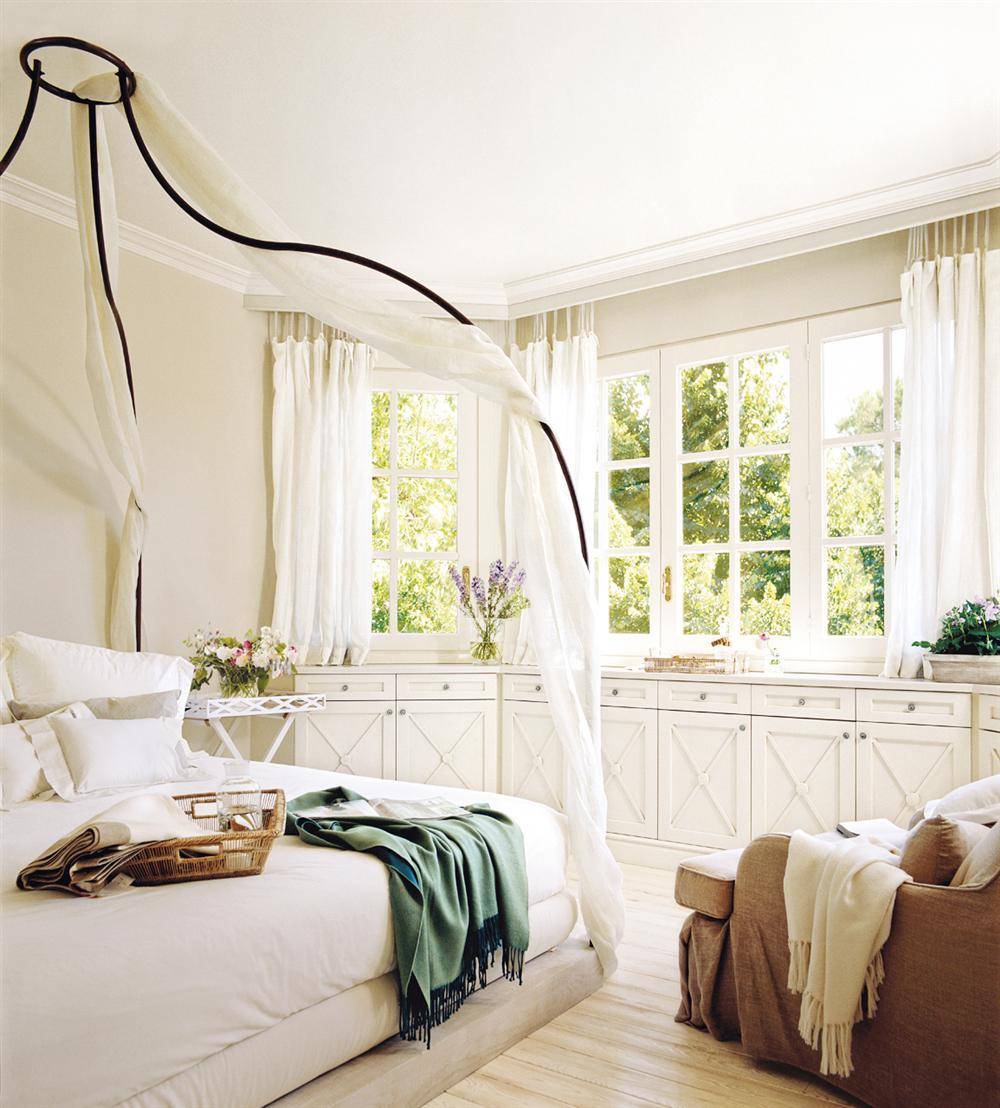 Dormitorio de verano con cama con dosel y muebles y ropa de cama blanca. 