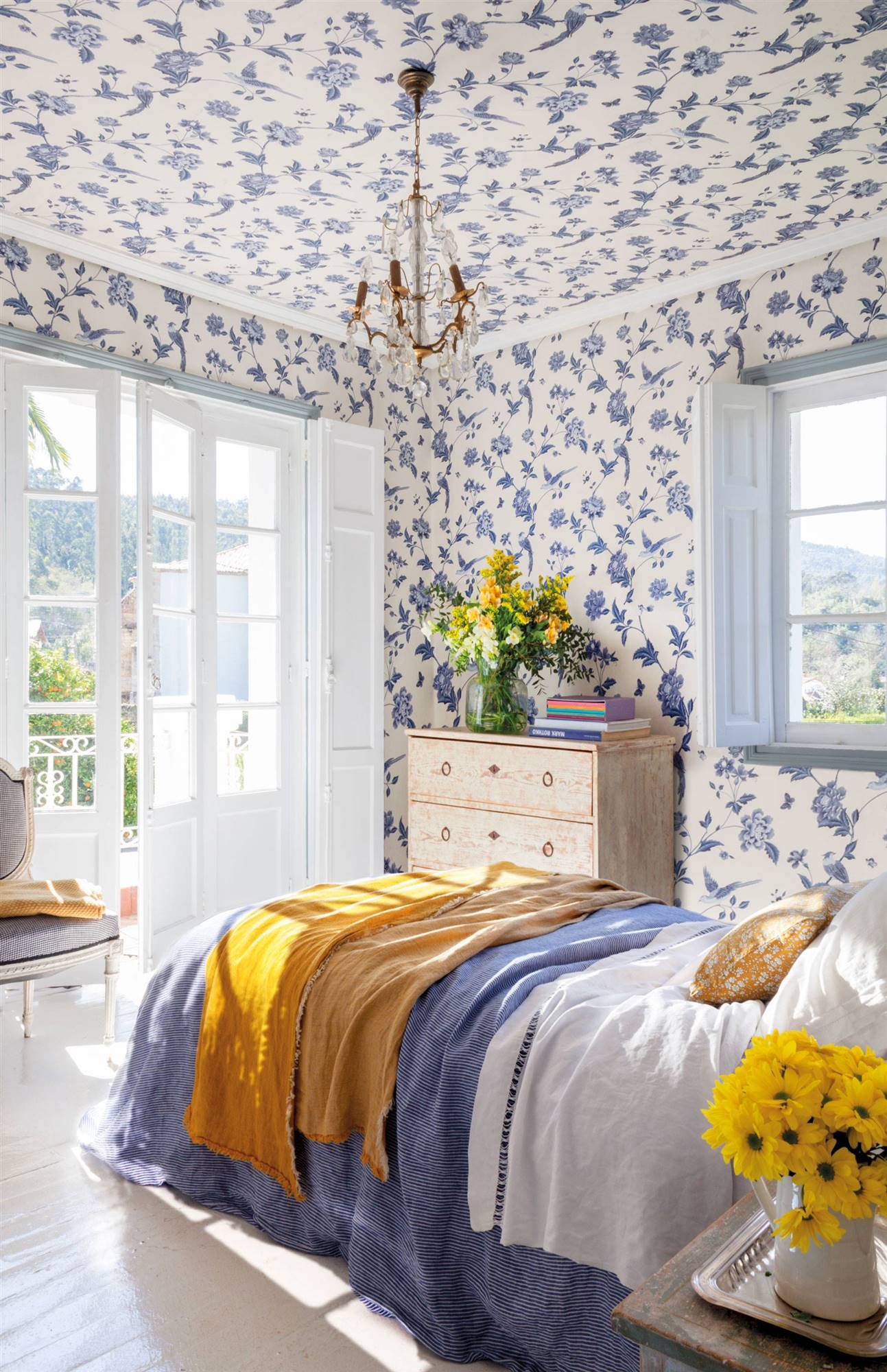 Dormitorio con papel pintado en paredes y techos con estampado de flores azules. 