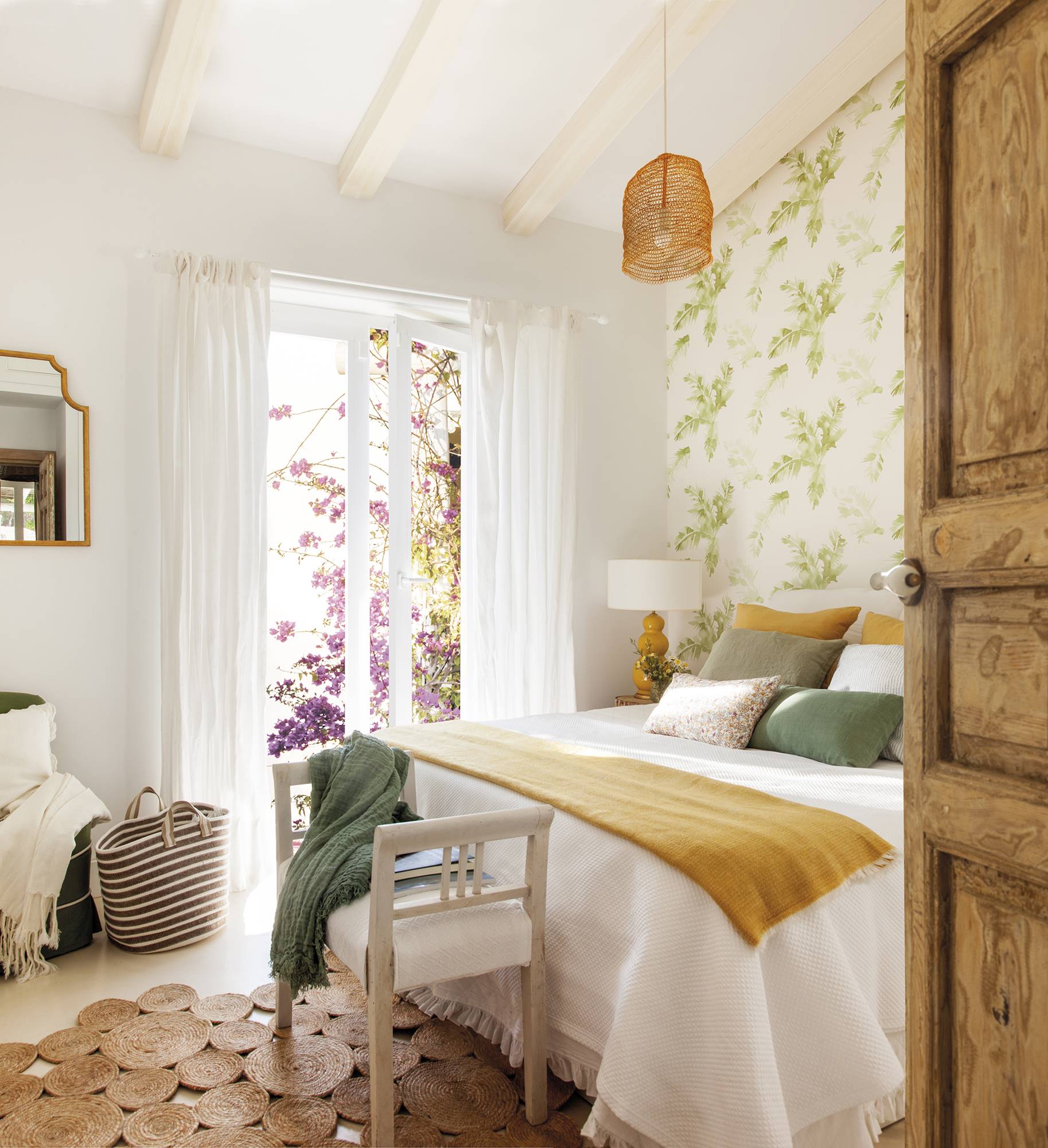 Dormitorio de verano con papel pintado con flores verdes en la pared del cabecero. 