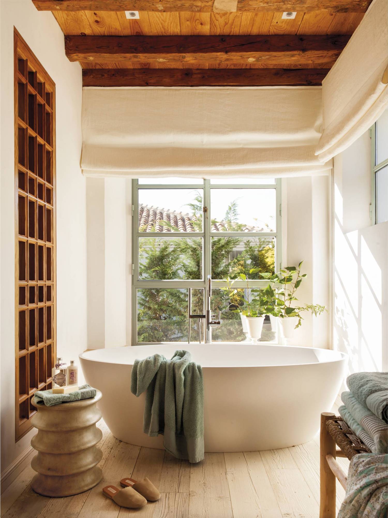Baño con bañera blanca exenta y un taburete de diseño con formas onduladas 480750