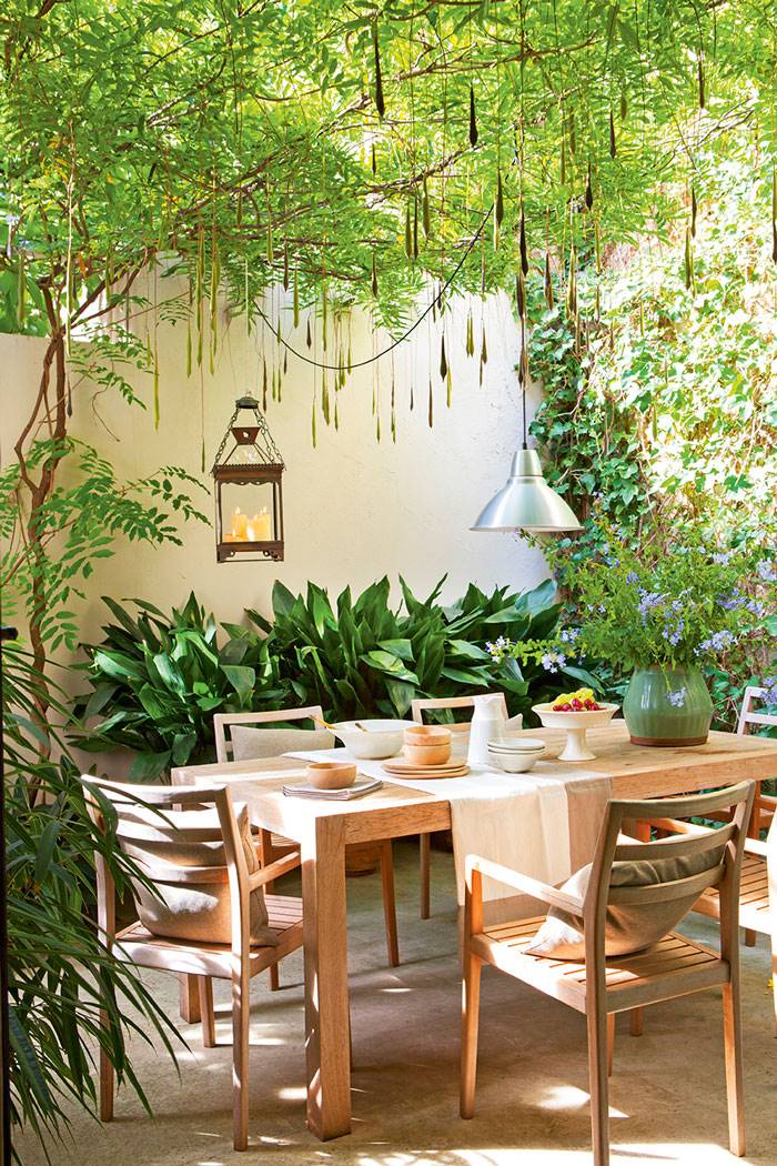 Patio decorado con comedor exterior y cubierta vegetal de plantas. 