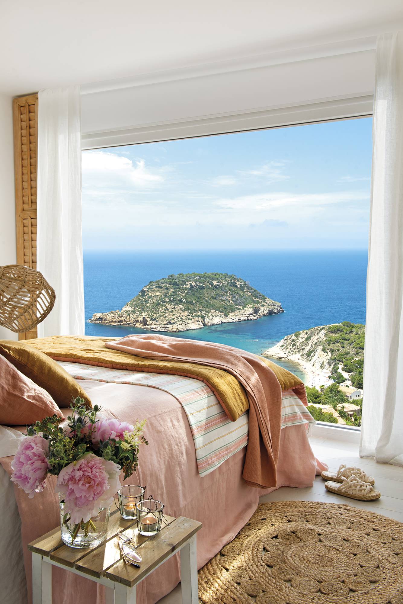 Dormitorio con pared a pie de cama de cristal con vistas al mar