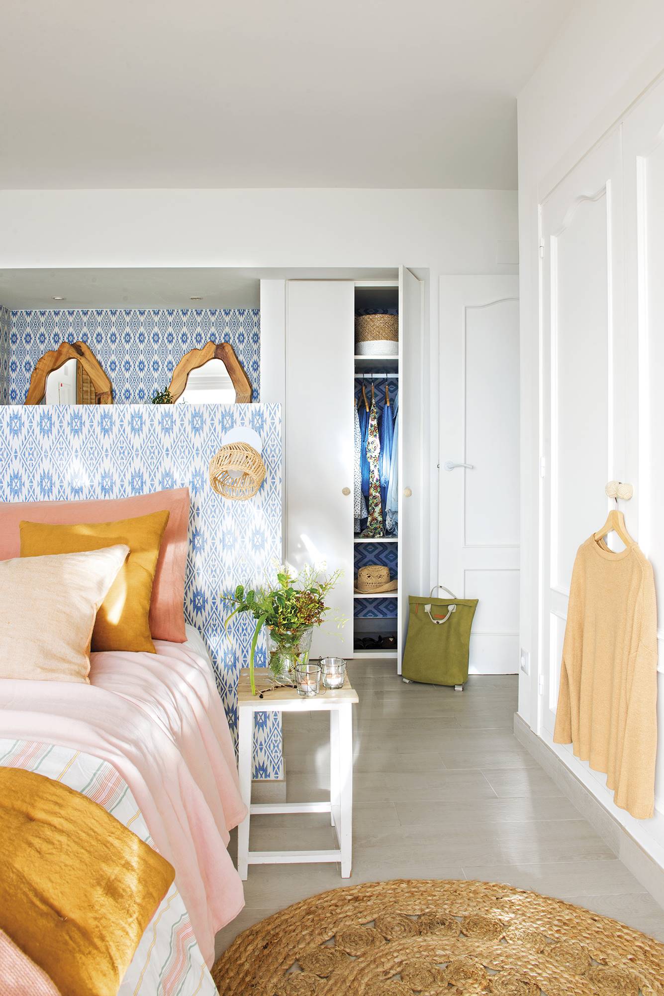 Dormitorio con cama en medio y zona de tocador al fondo con papel pintado con motivos azules