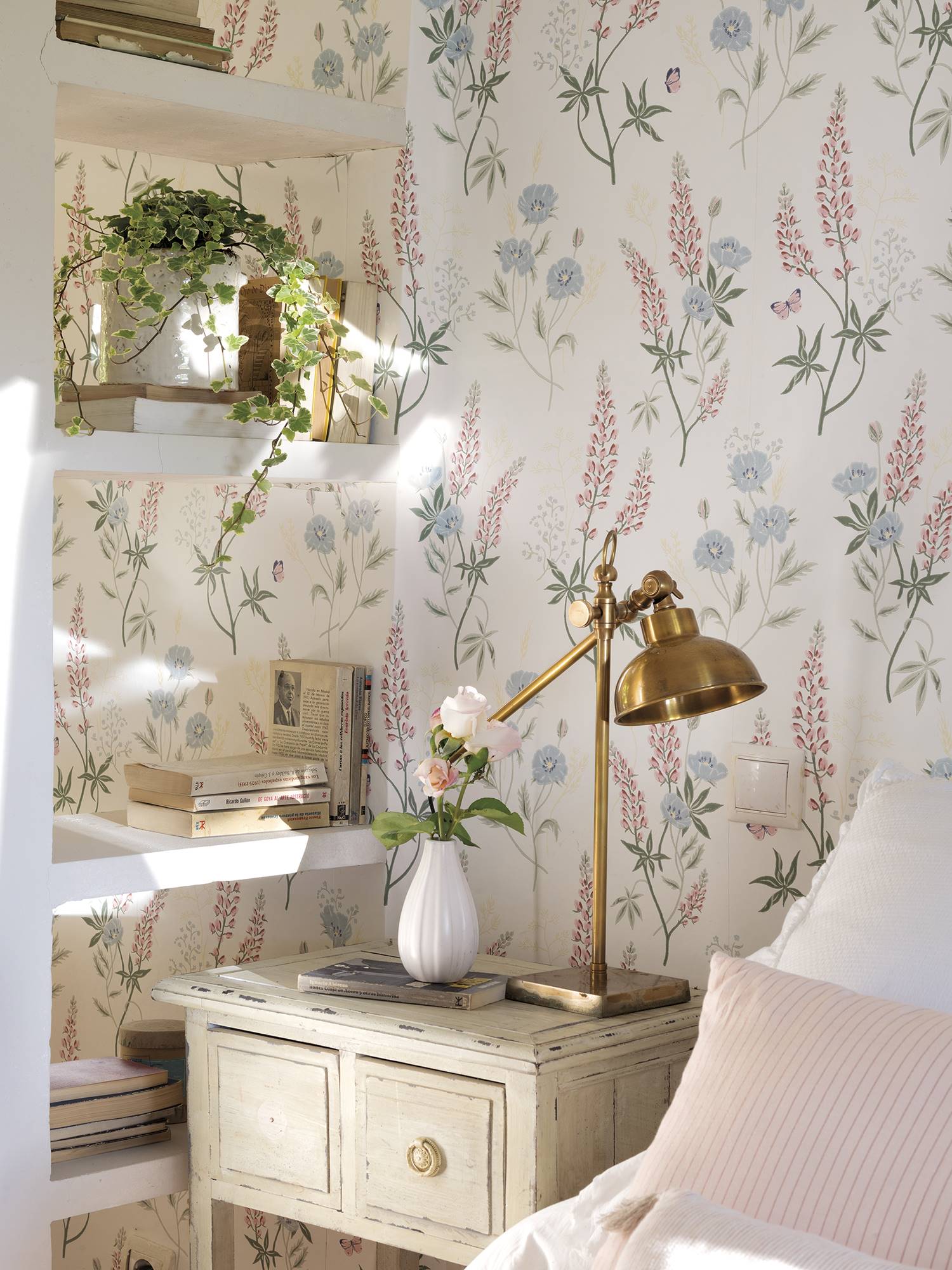 Detalles de un dormitorio en tonos rosa pastel y beige con papel pintado en la pared con motivos florales 
