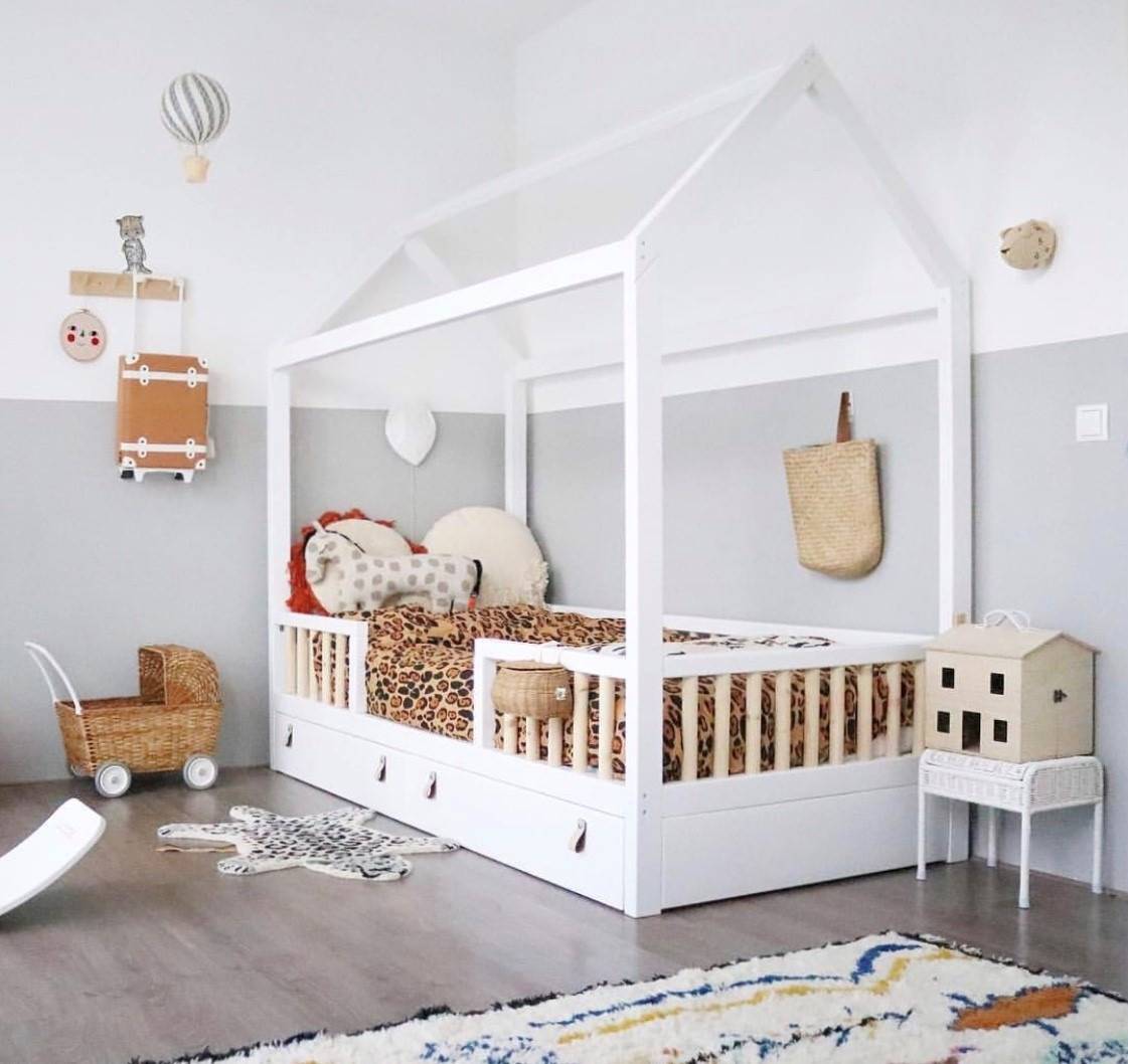 Habitación infantil decorada con el método Montessori con la cama en una estructura con forma de casita blanca
