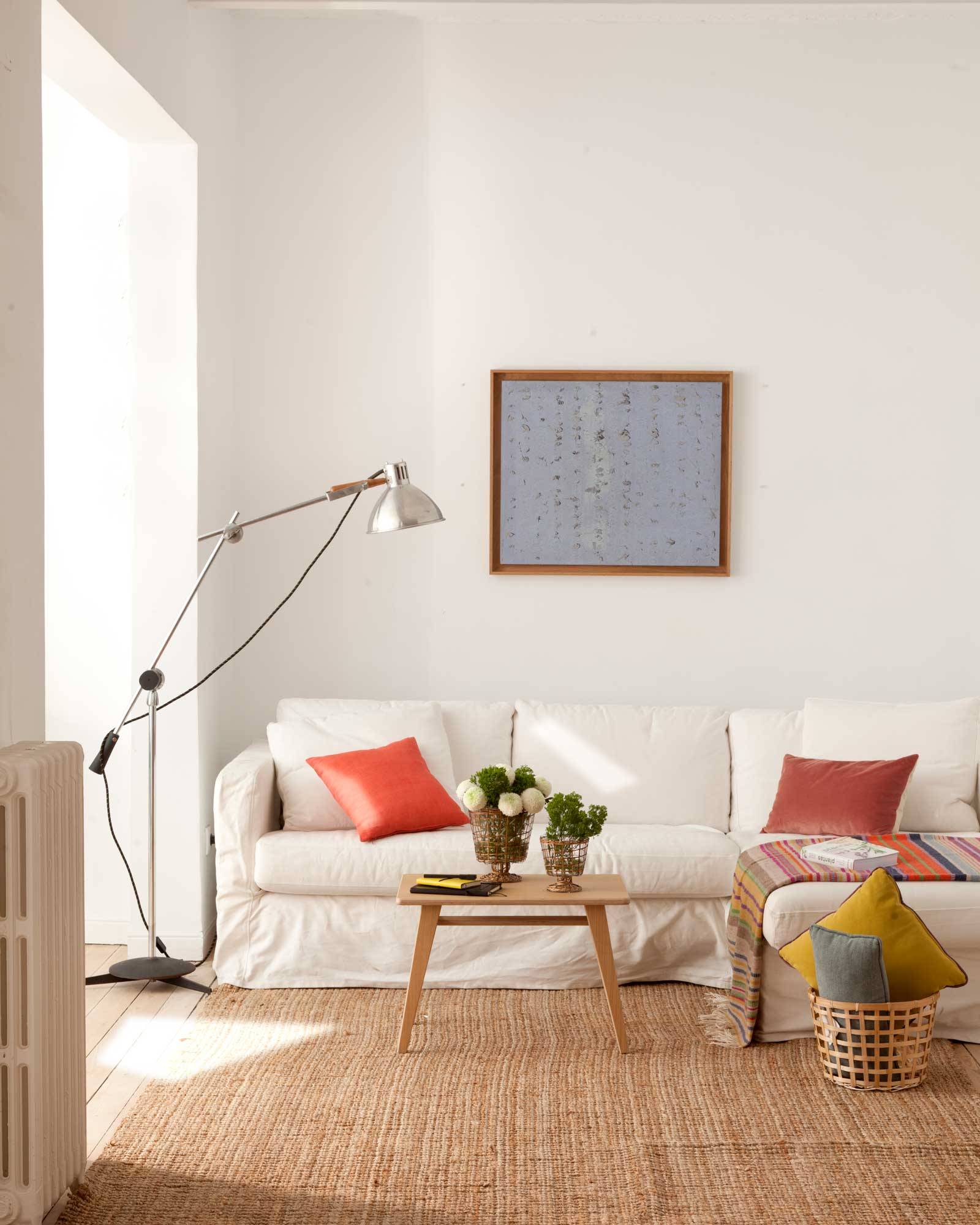 Salón con sofá cubierto con una funda de color blanco. 