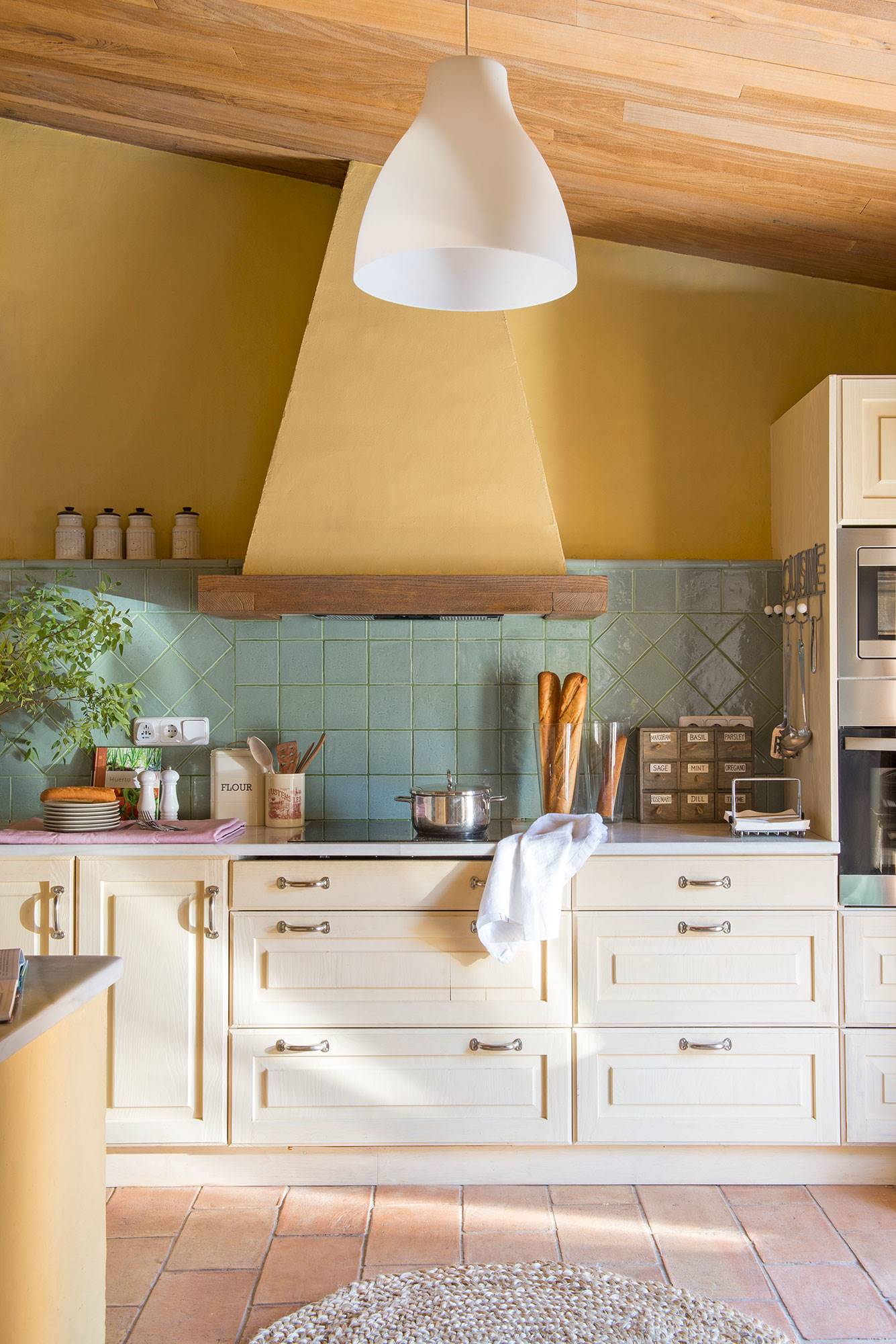 Cocina rústica con toques modernos con paredes de color mostaza y techo de madera. 