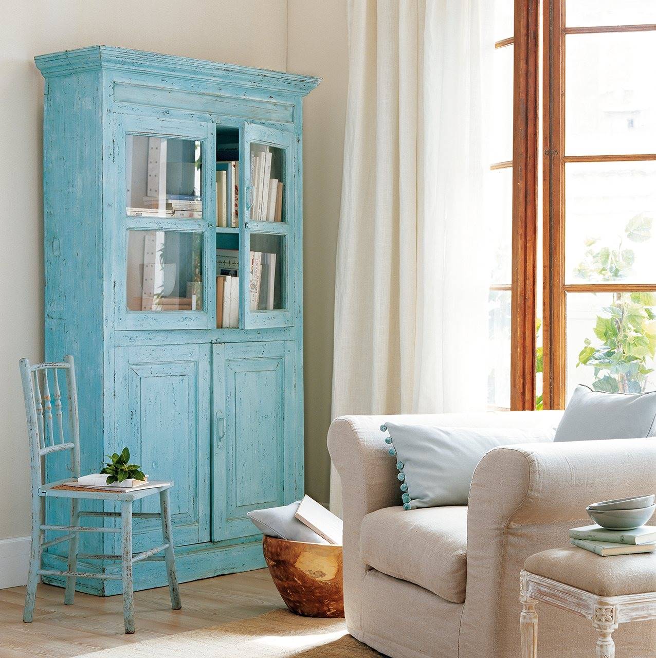 Sala de estar con armario en tono azul decapado y sillón beige