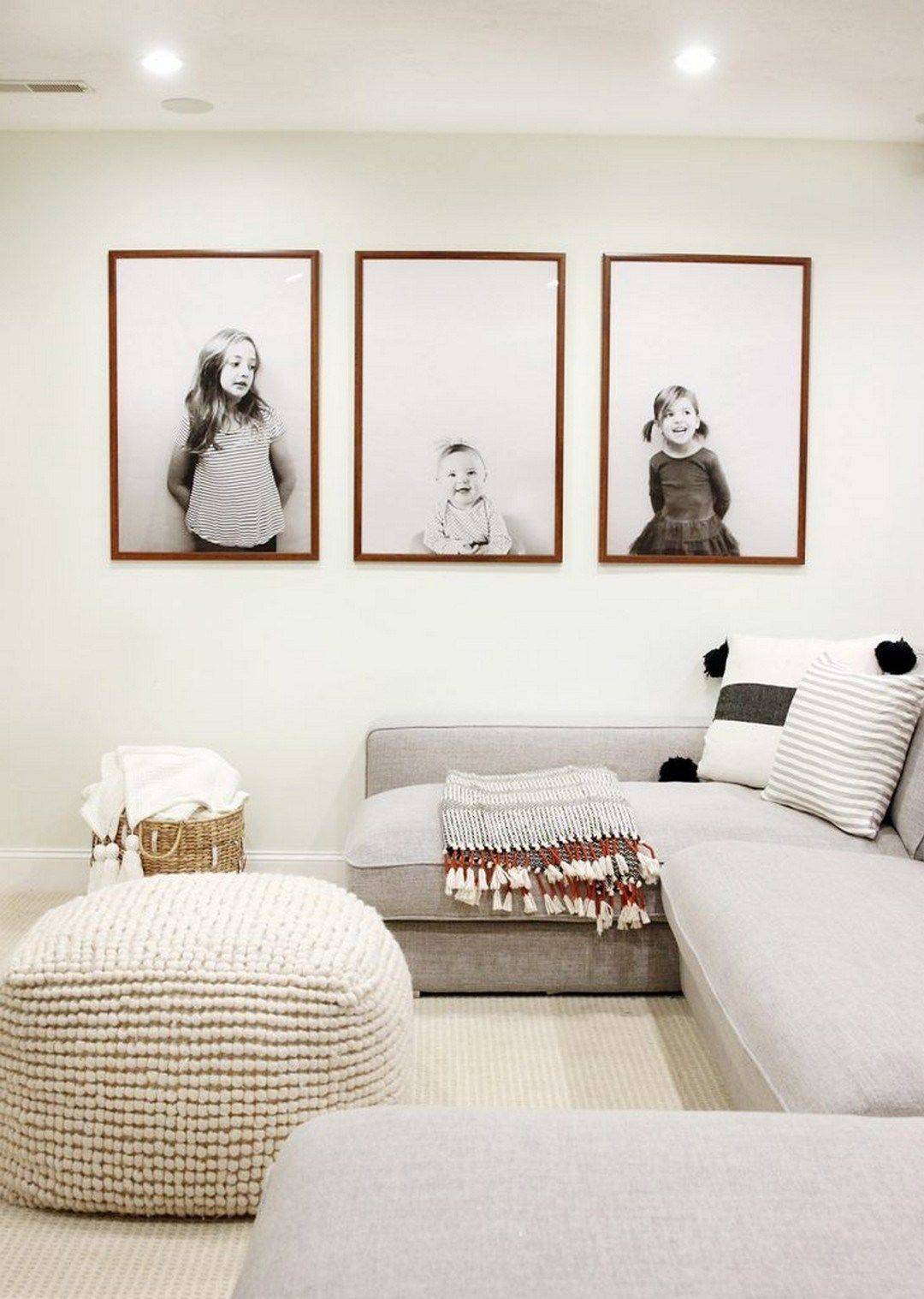 Salón boho con sofá modular gris, puf, cesta de fibras y fotos familiares en blanco y negro en la pared