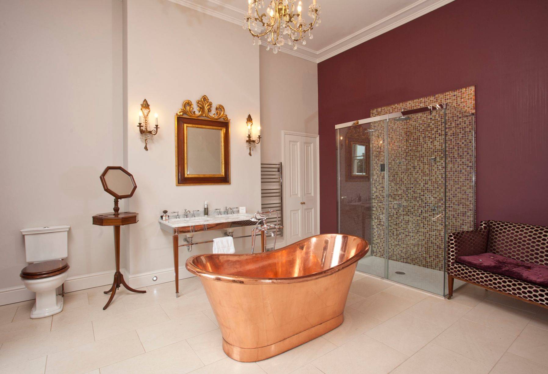 Baño de estilo clásico con bañera de cobre y lámpara de araña