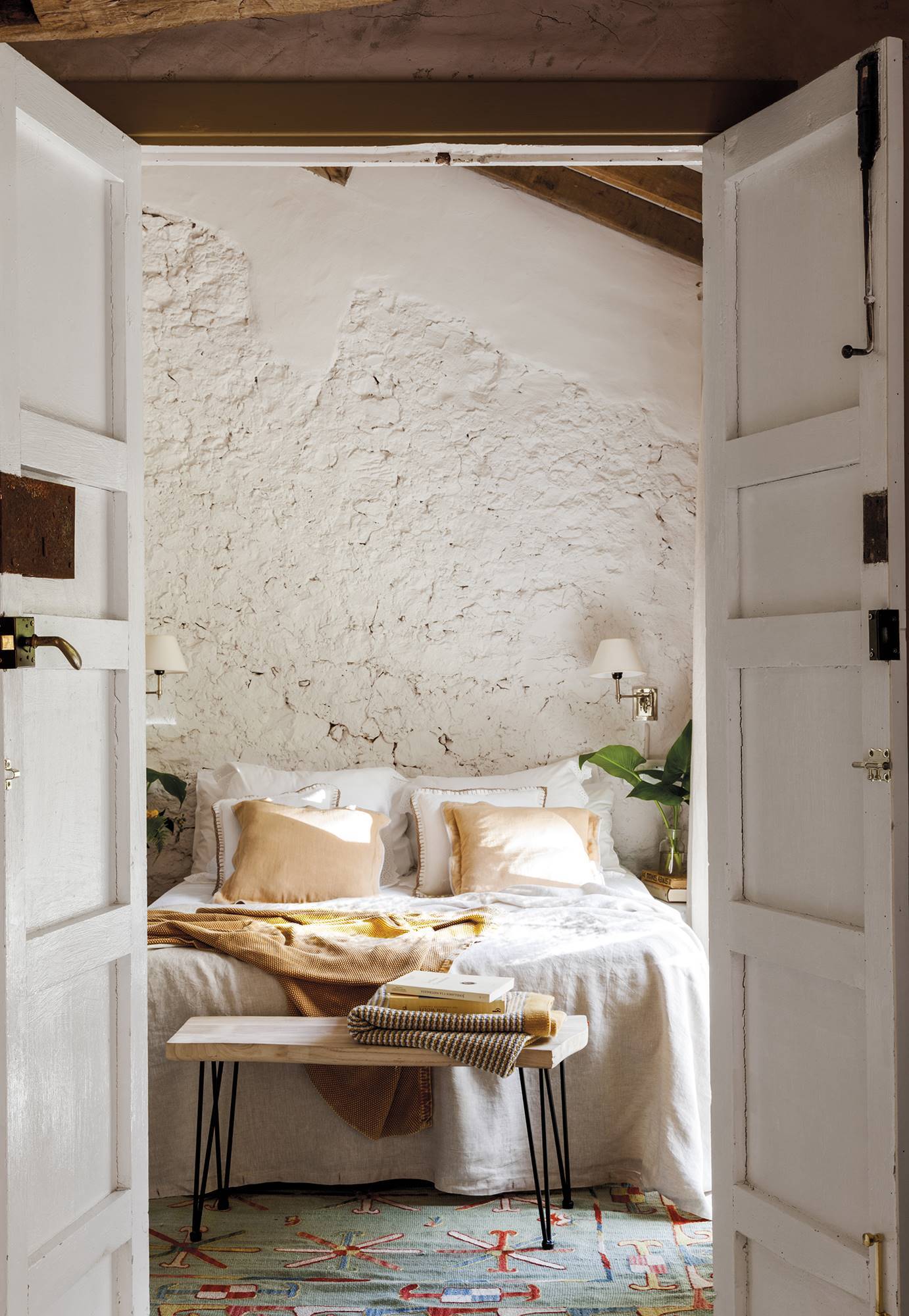Dormitorio de casa rural con paredes de piedra en blanco