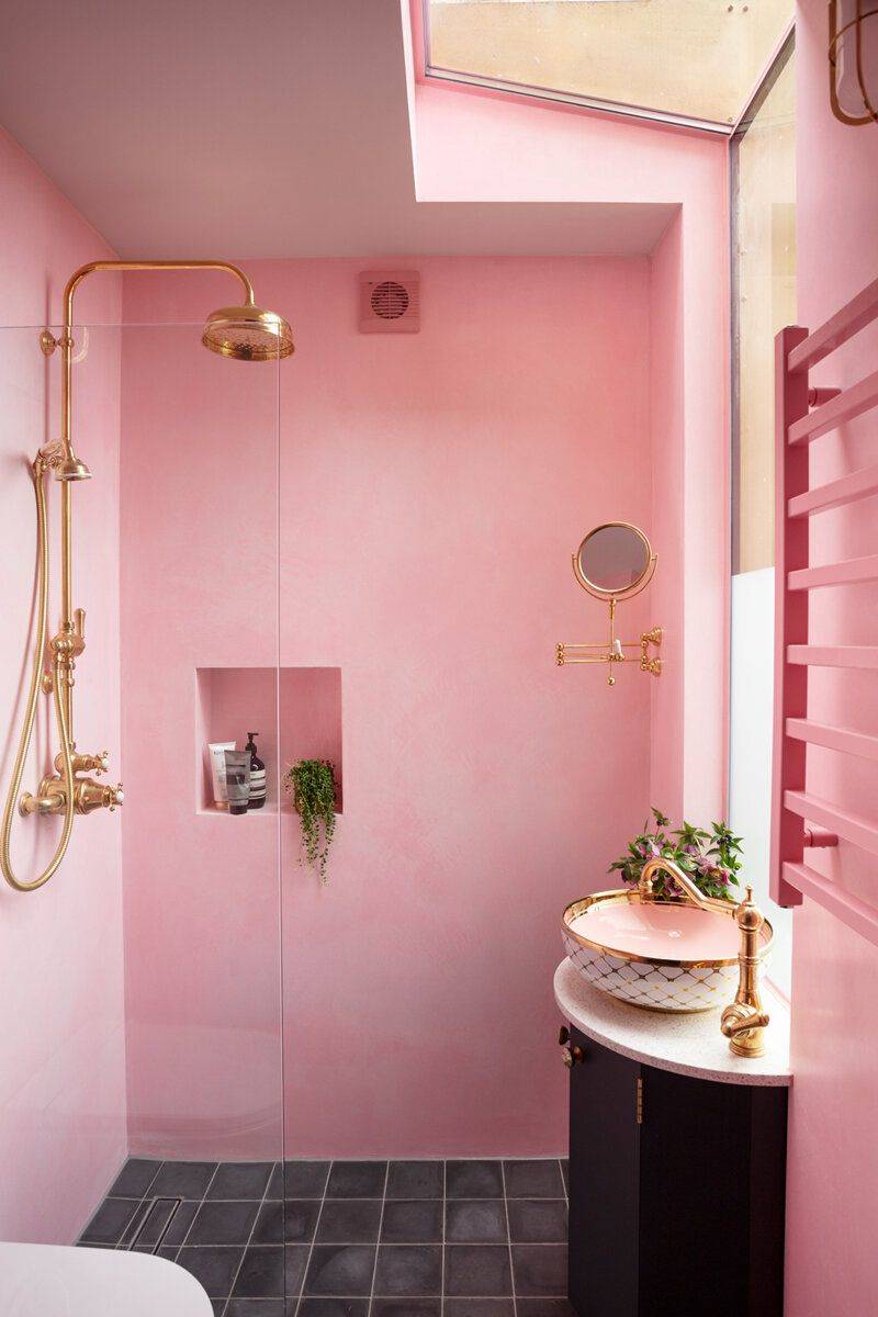 Baño con ducha de obra decorado en rosa con grifería dorada