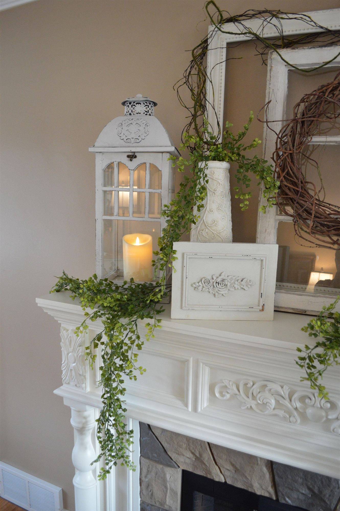 Chimenea decorada con un farolillo grande, vela LED y un jarrón con una planta trepadora