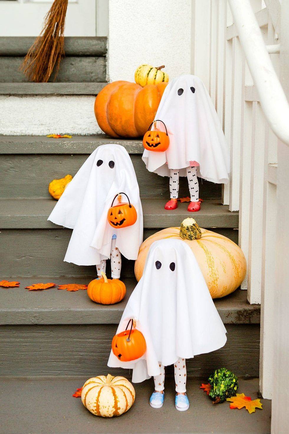 Decoración de Halloween con fantasmas con piernas de muñecos en las escaleras.