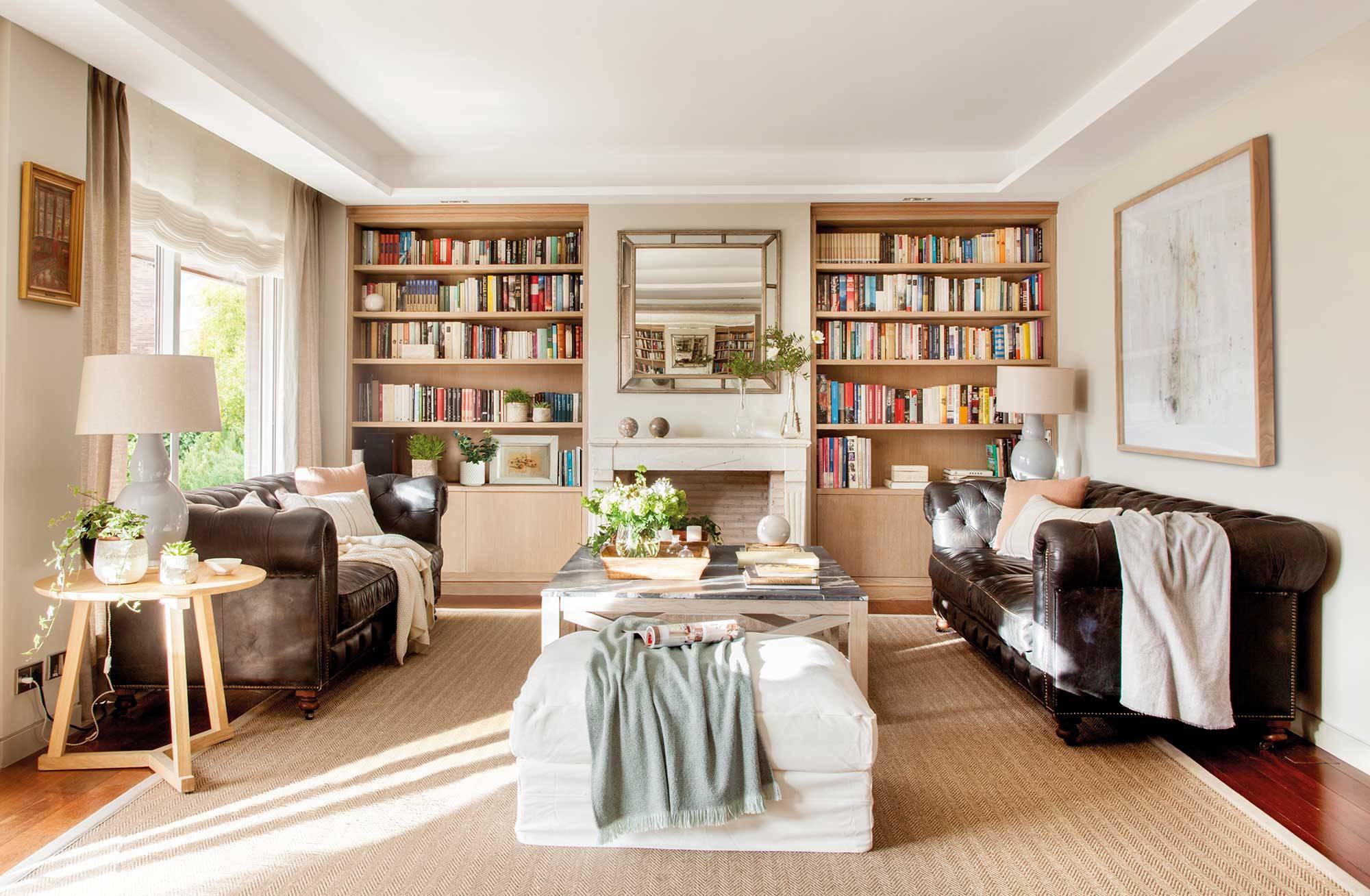Salón clásico actual con librería y dos sofás chéster. 