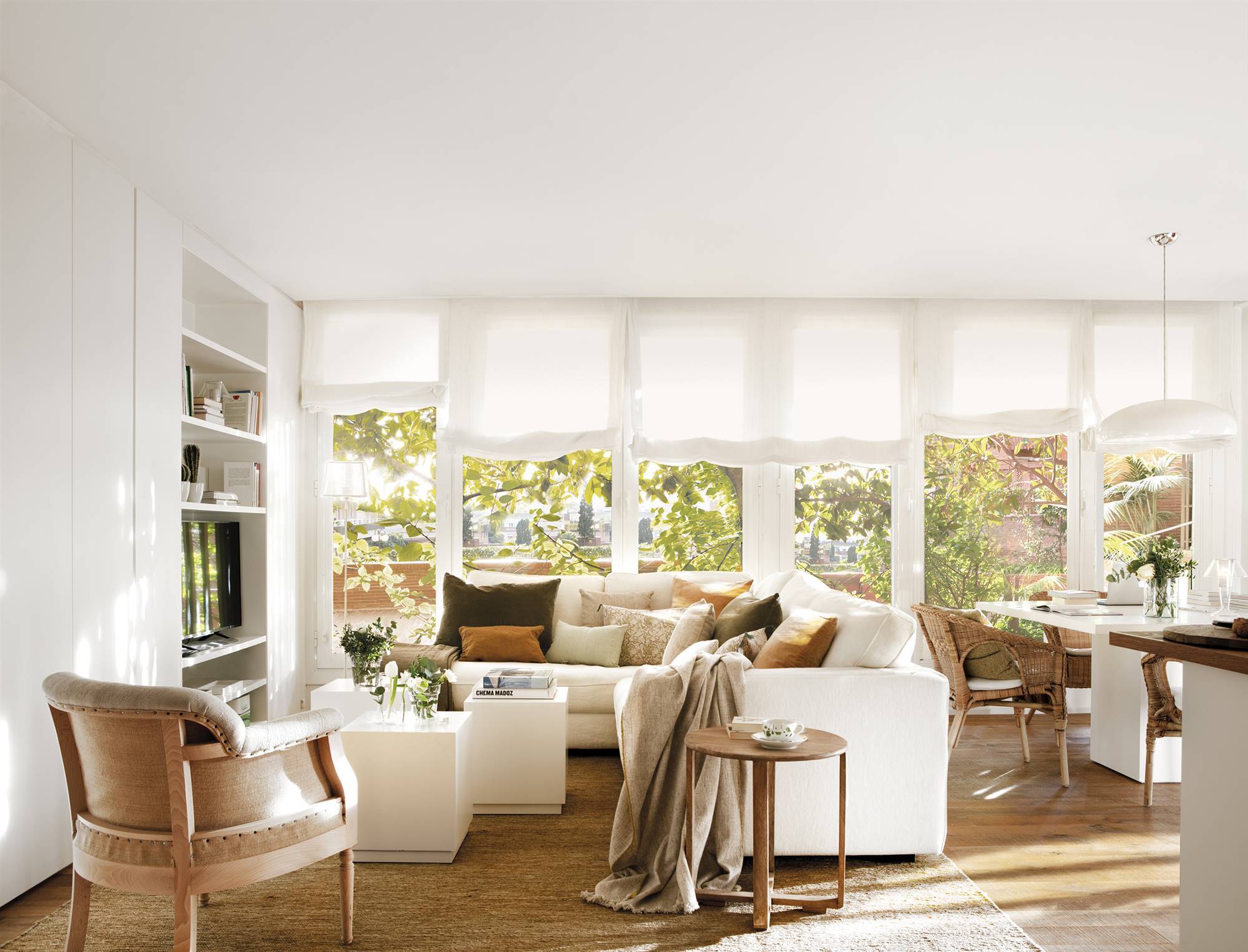 Salón blanco con sofá rinconero y grandes ventanales 