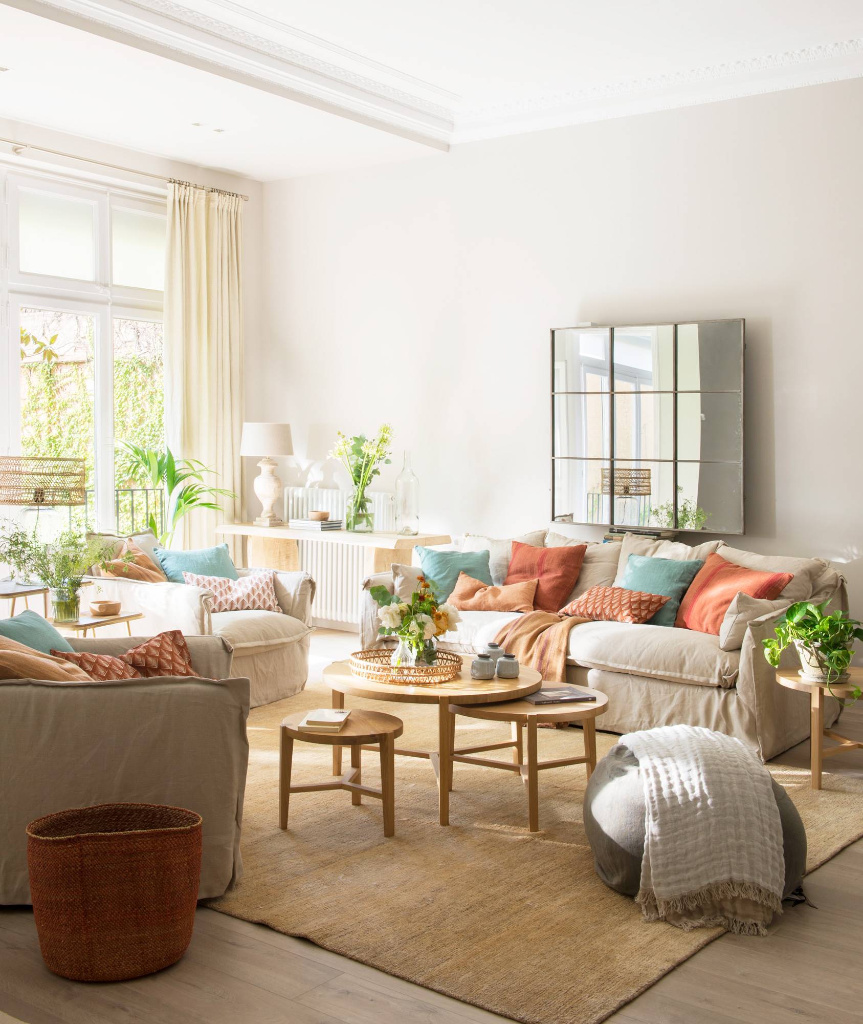 Salón con sofás beige, cojines azules y rojos y alfombra de fibra natural.