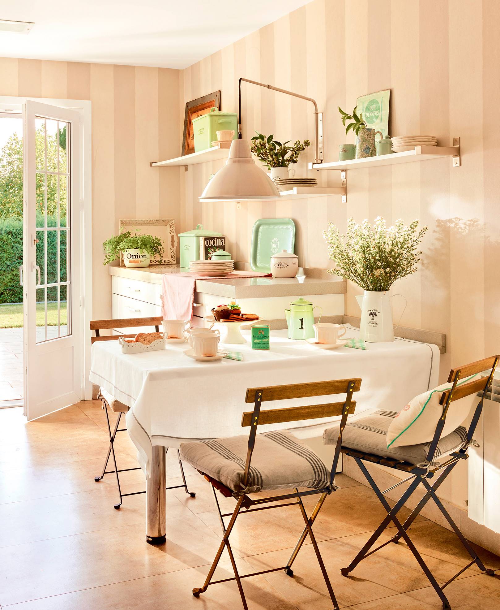 Comedor con mesa fijada a la pared, sillas plegables, accesorios vintage y estanterías. 