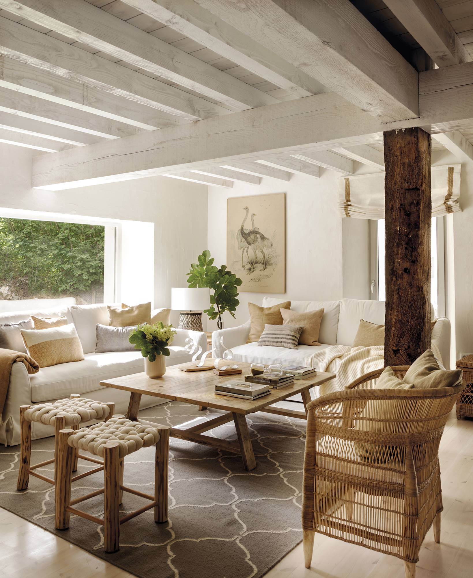 Salón con sofás blancos con muebles de fibras y vigas en el techo. 