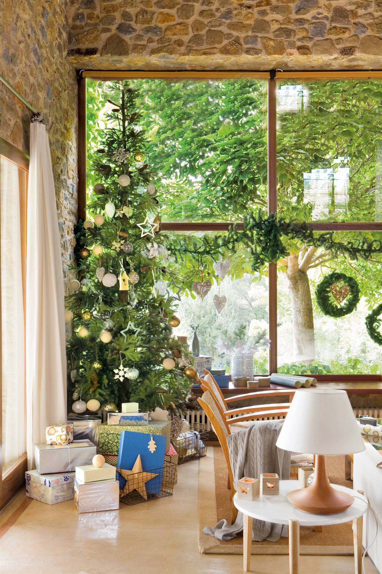 Salón rústico muy navideño con paredes de piedra y árbol de Navidad.
