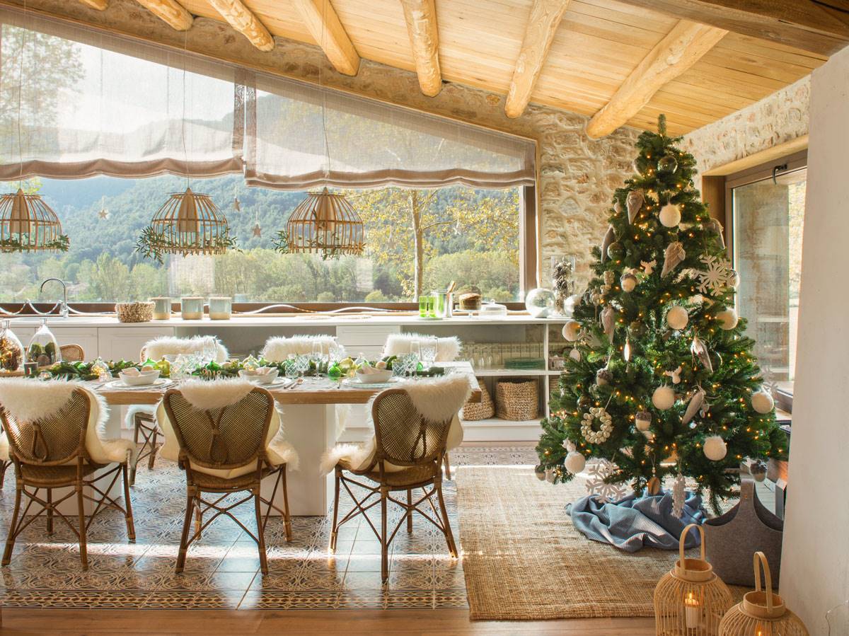 Comedor de estilo rústico con techo abuhardillado con vigas y mesa de madera decorada para la Navidad.
