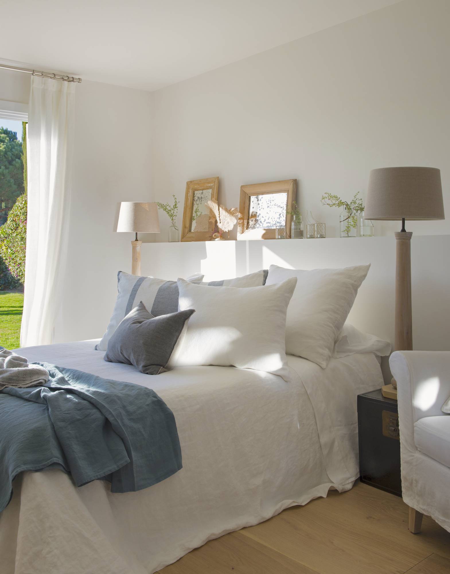 dormitorio con cama y paredes blancas con cojines azules 00480399