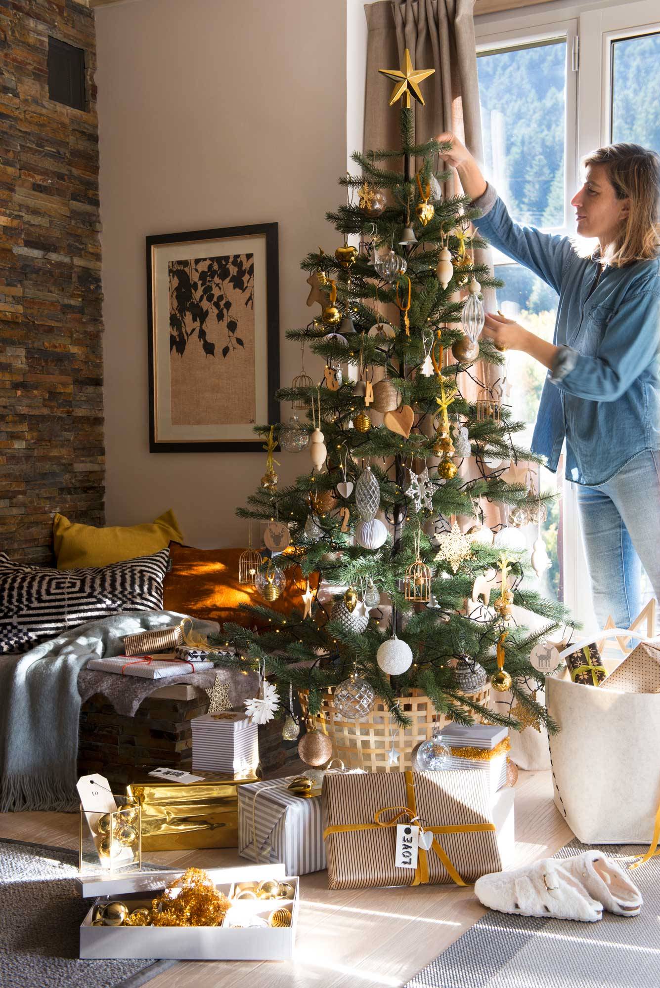 Salón con mujer adornando el árbol de Navidad.