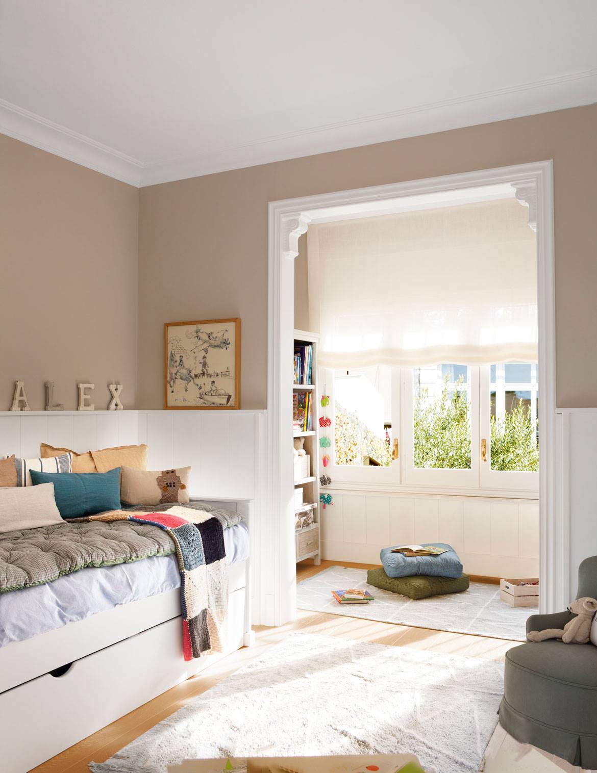 Habitación infantil con paredes pintadas color beige, alfombras, arrimadero y cama nido.
