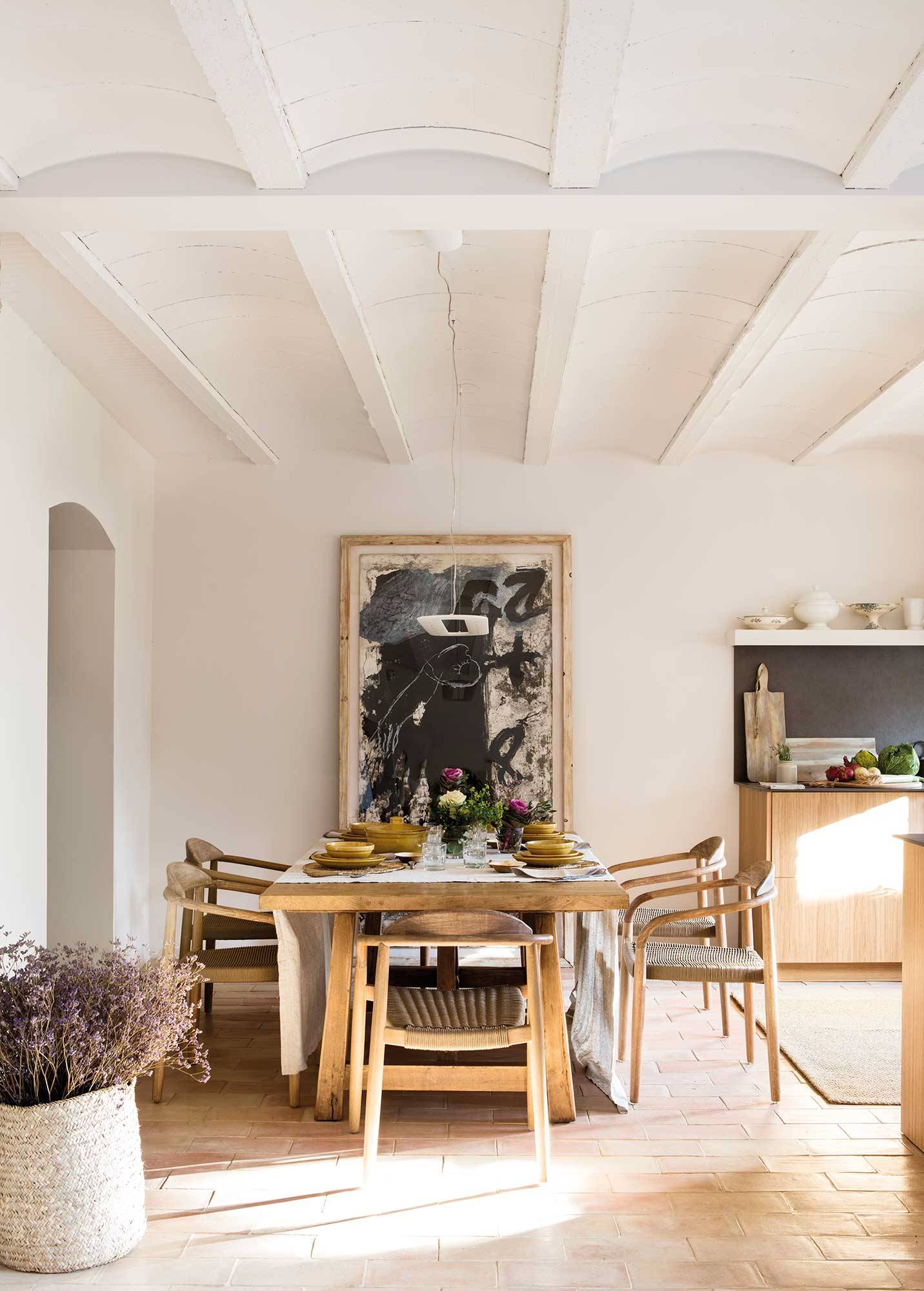Comedor abierto a la cocina con mesa rústica y sillas de madera.