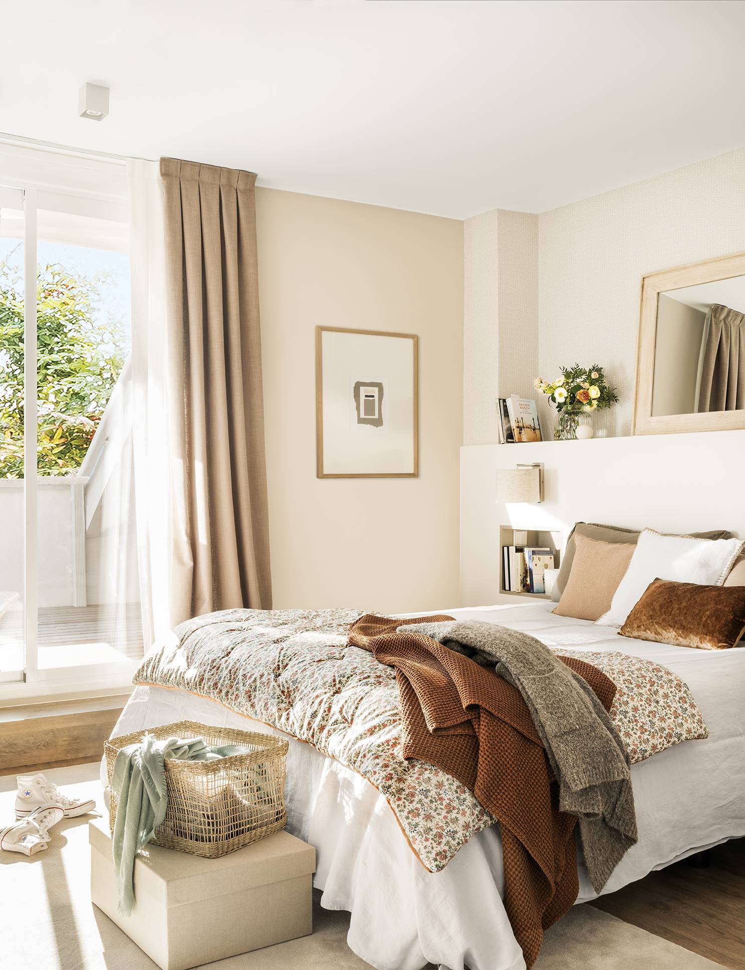 Dormitorio con paredes beige y ropa de cama blanca y en tonos tostados. 