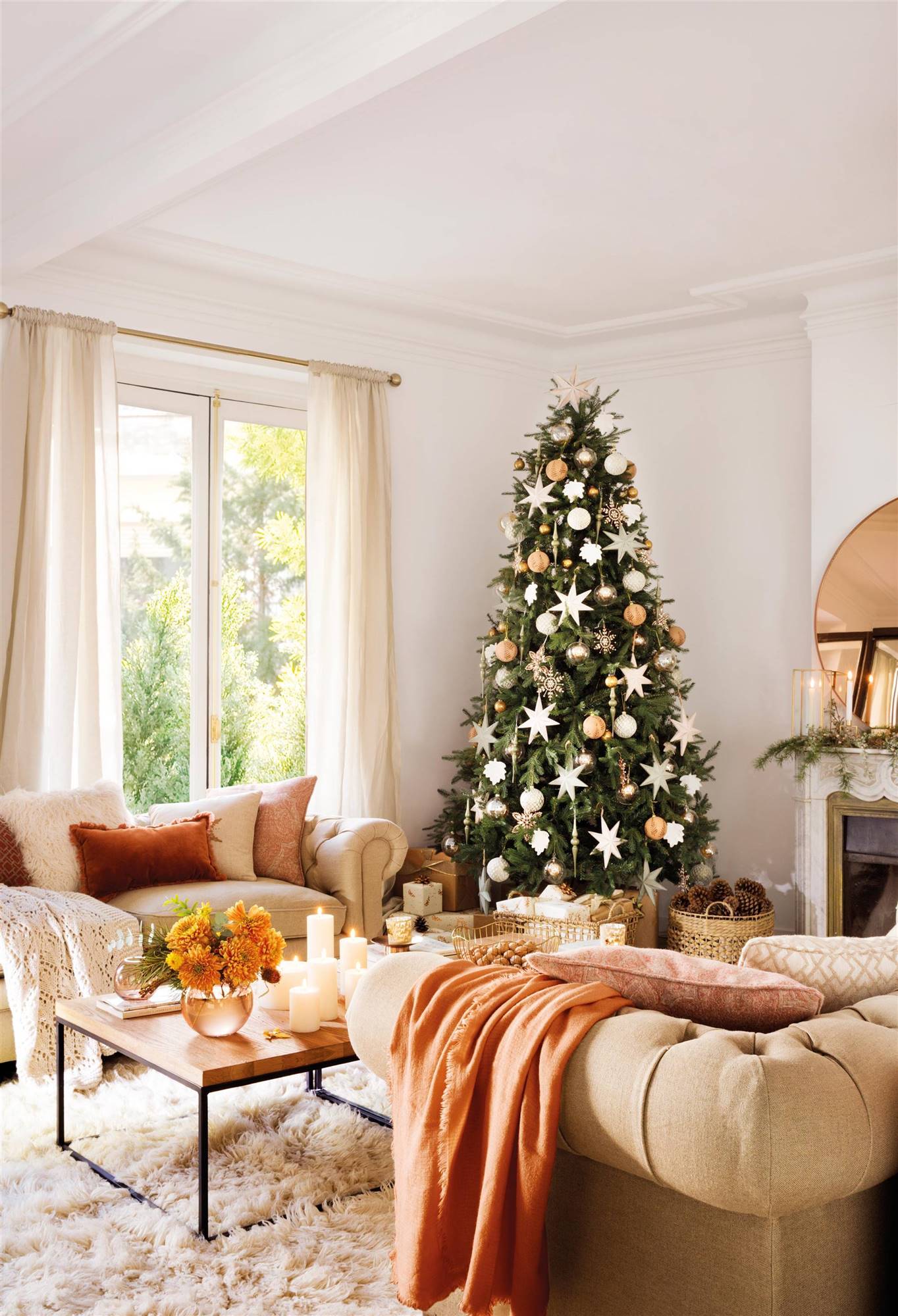 Salón con chimenea, sofás crema y árbol de Navidad decorado en plateado y bronce. 