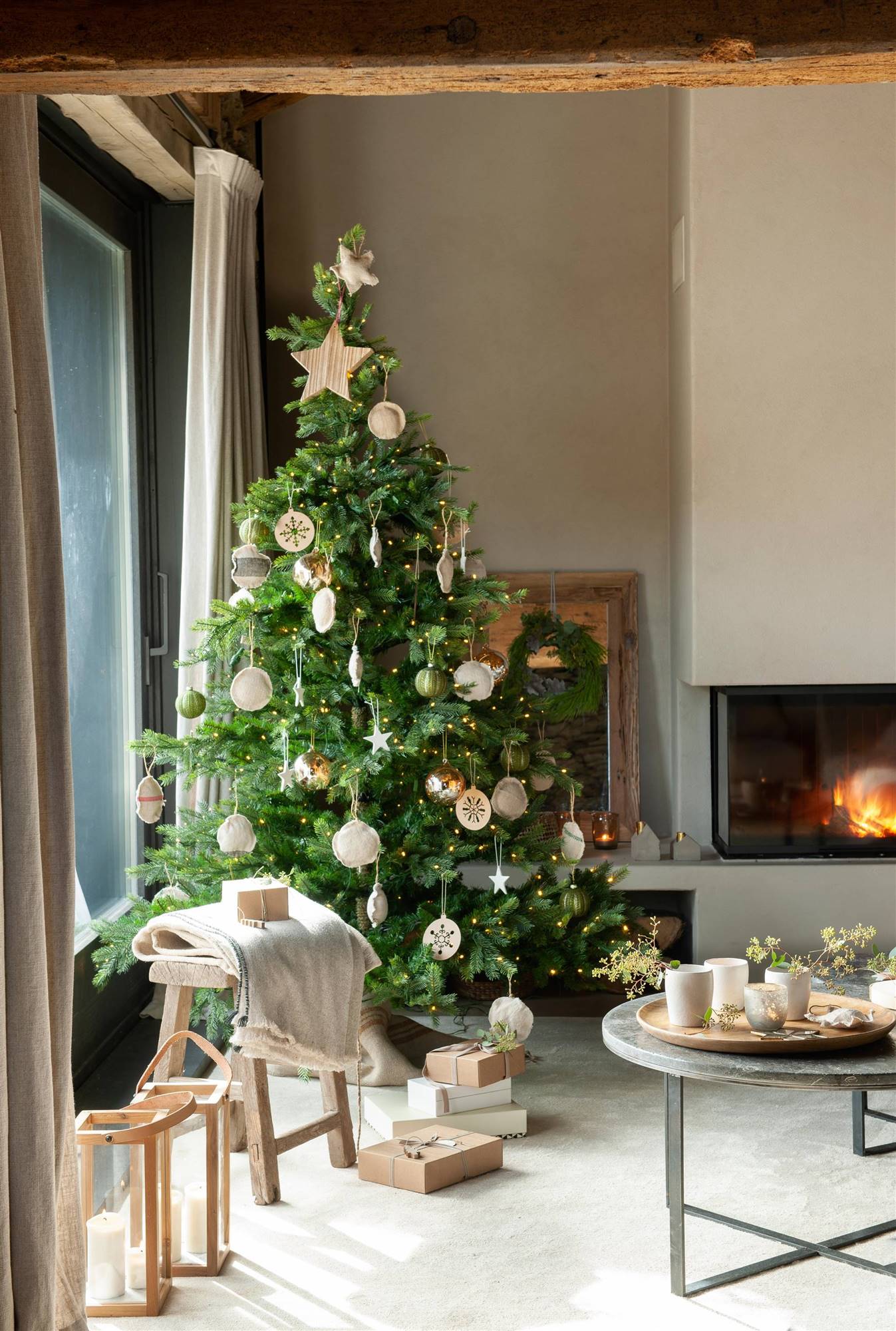 Salón con árbol de Navidad decorado con adornos al lado de la chimenea.