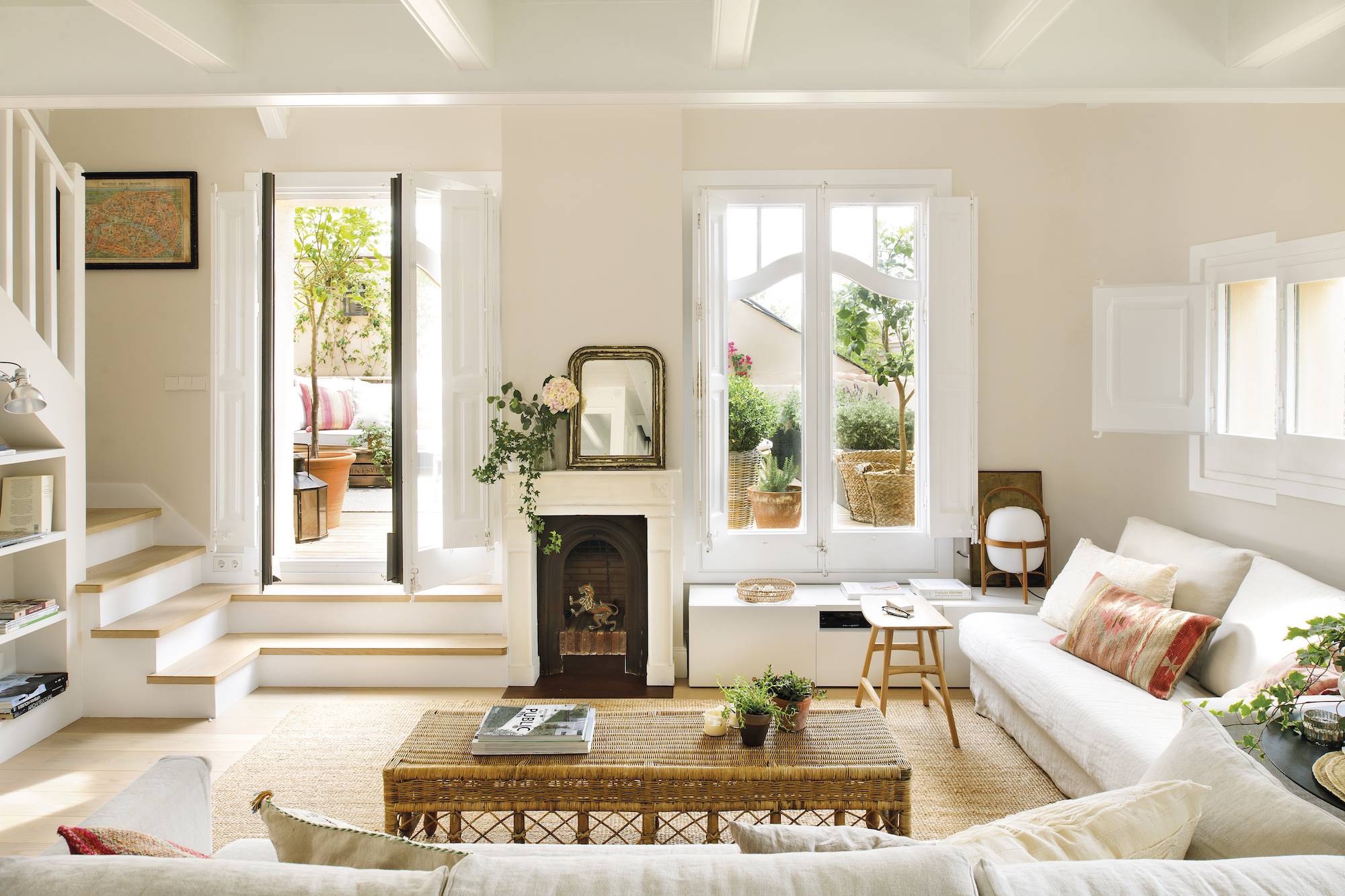Salón con sofás blancos, paredes en color beige y mini chimenea.