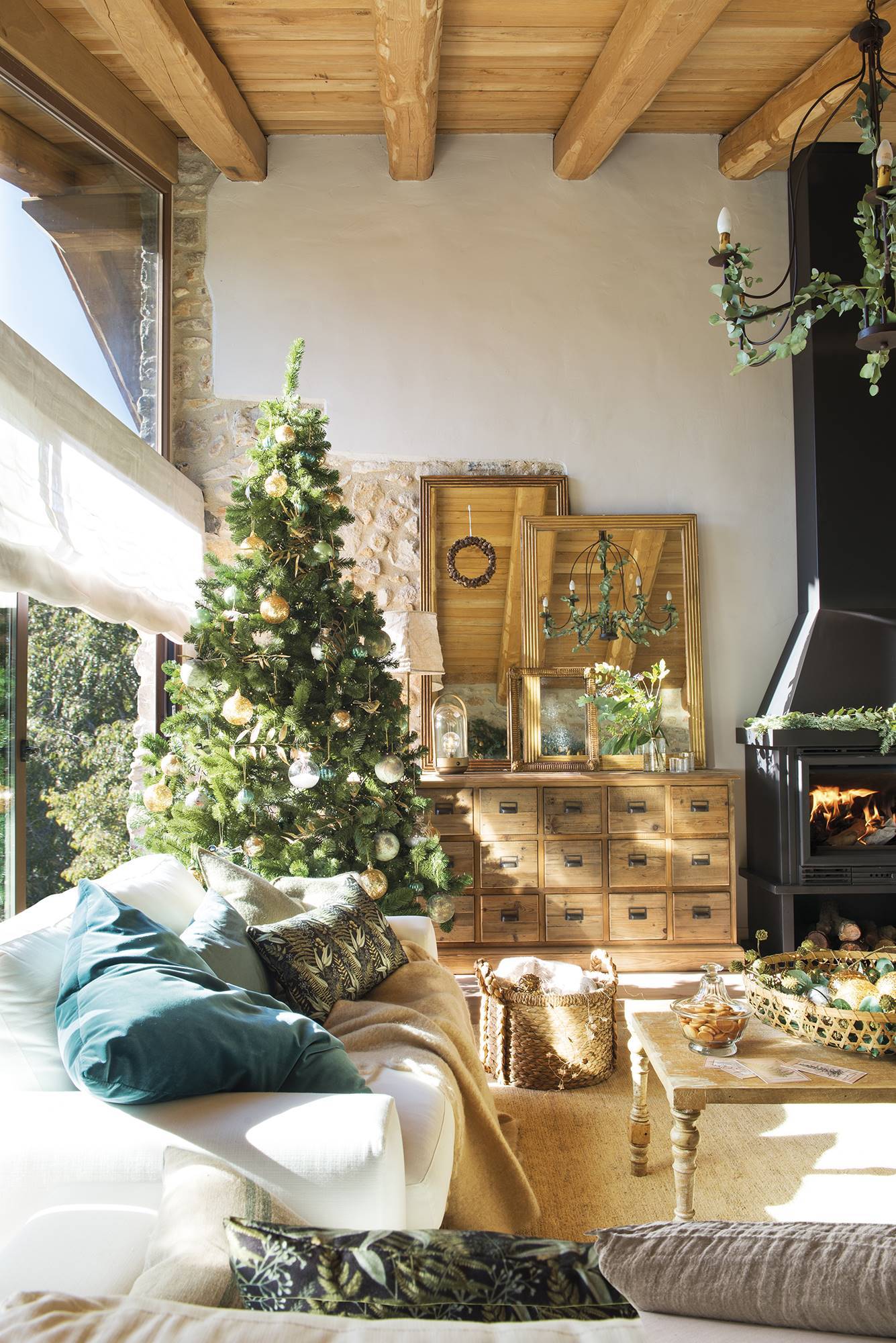 Salón rústico con árbol de Navidad junto a la ventana. 