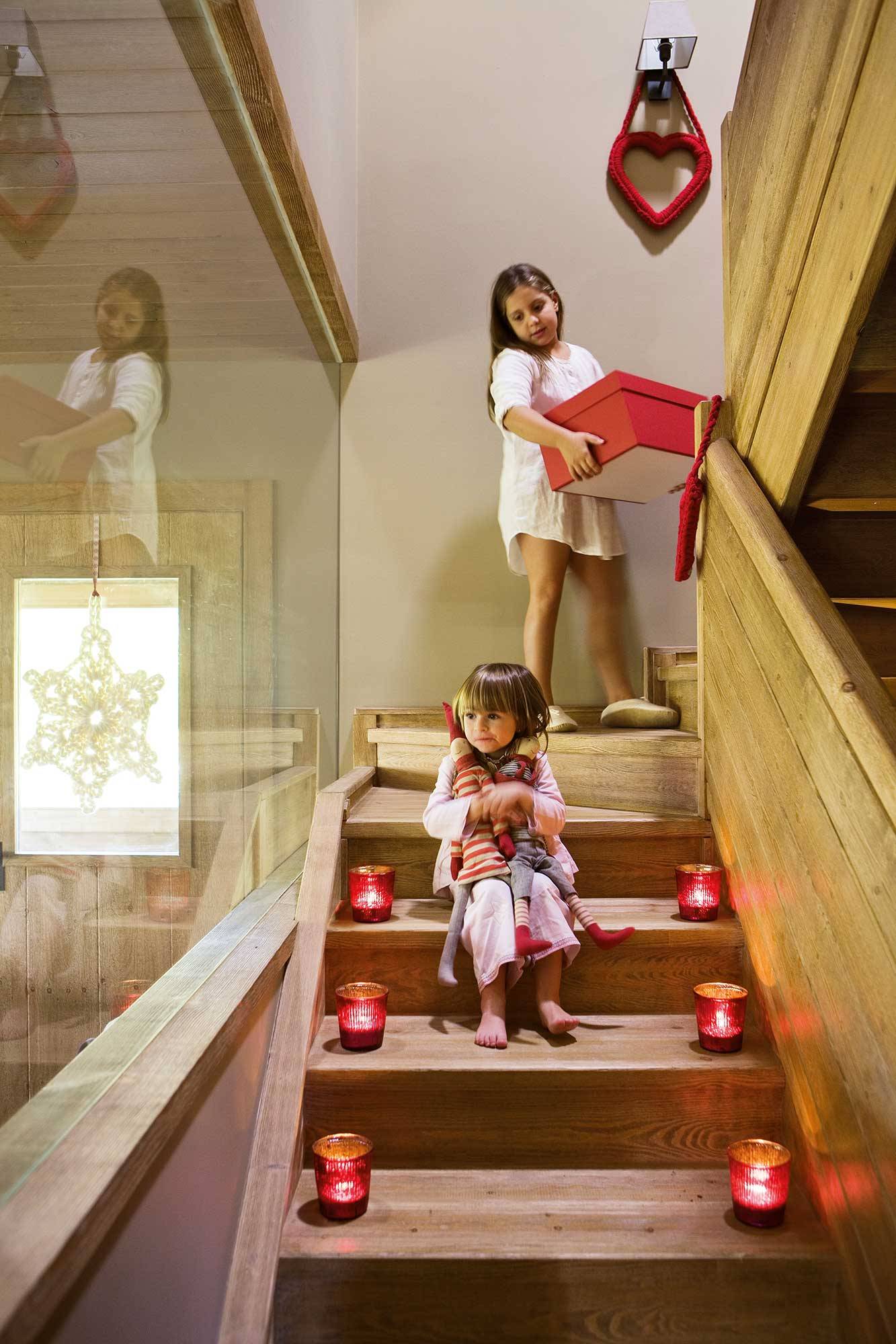 Escalera de casa de montaña con dos niñas y portavelas rojos_00374158